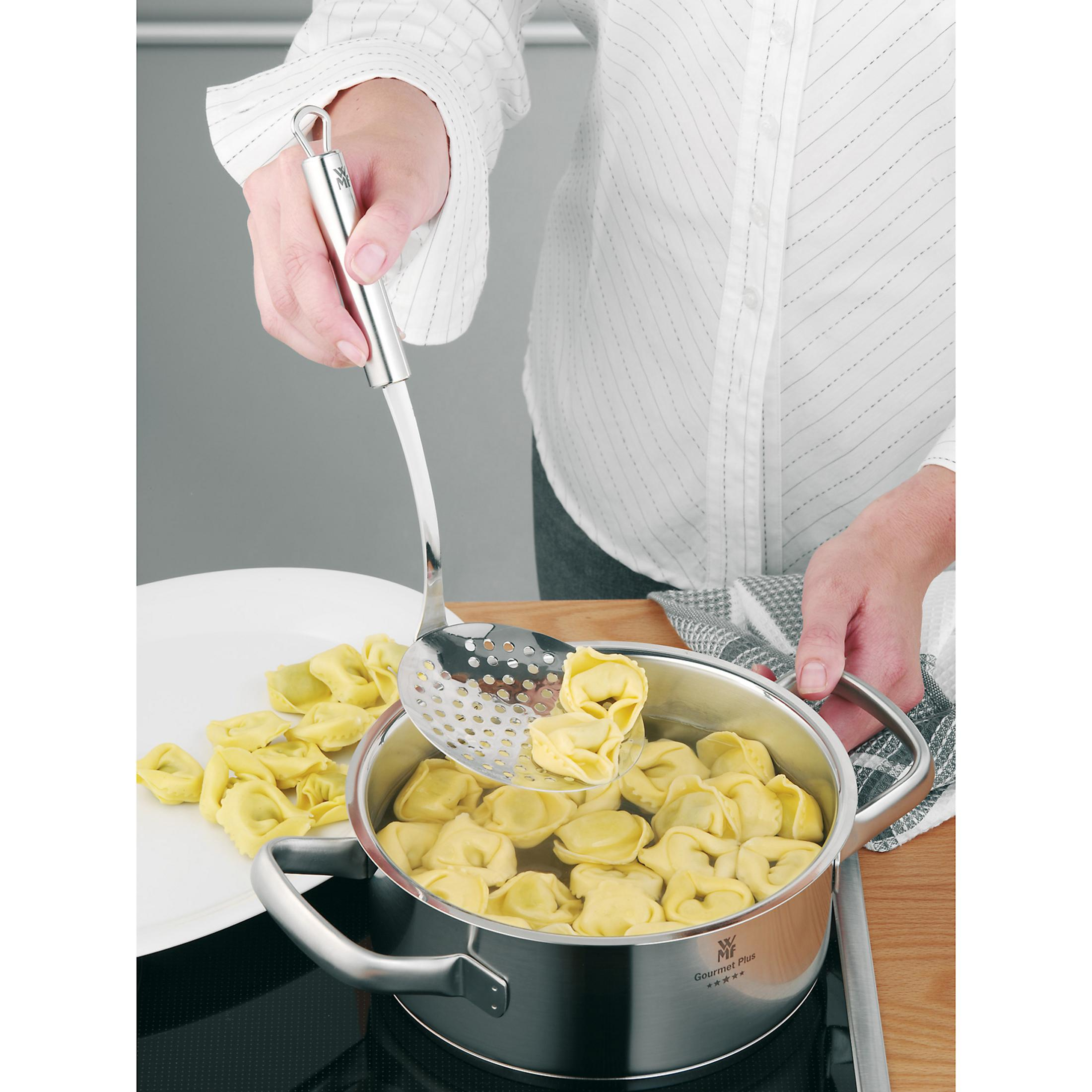 Bir kişi, pişmiş tortellini'yi paslanmaz çelik bir tencereden çıkarmak için delikli bir kaşık kullanıyor.