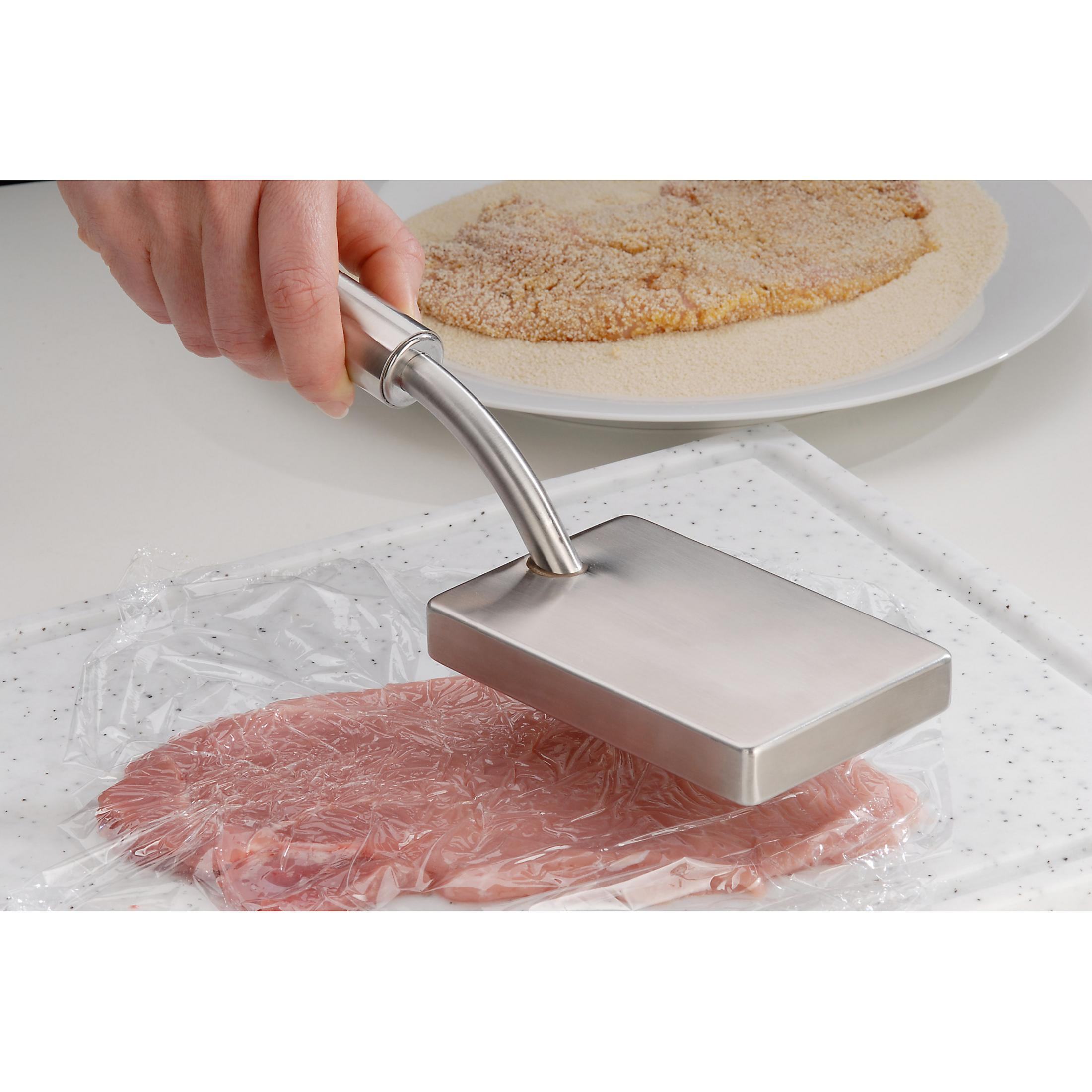 Person drückt Fleischklopfer auf Fleisch, das mit Plastikfolie bedeckt ist. Paniertes Fleisch im Hintergrund.