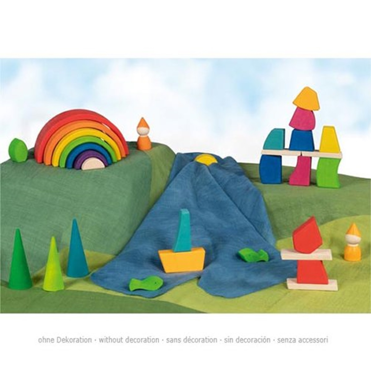 Holzspielzeugszene: Regenbogen, Zwerge, Boot und geometrische Formen auf grünem Tuch. Hintergrund ist ein blauer Himmel.