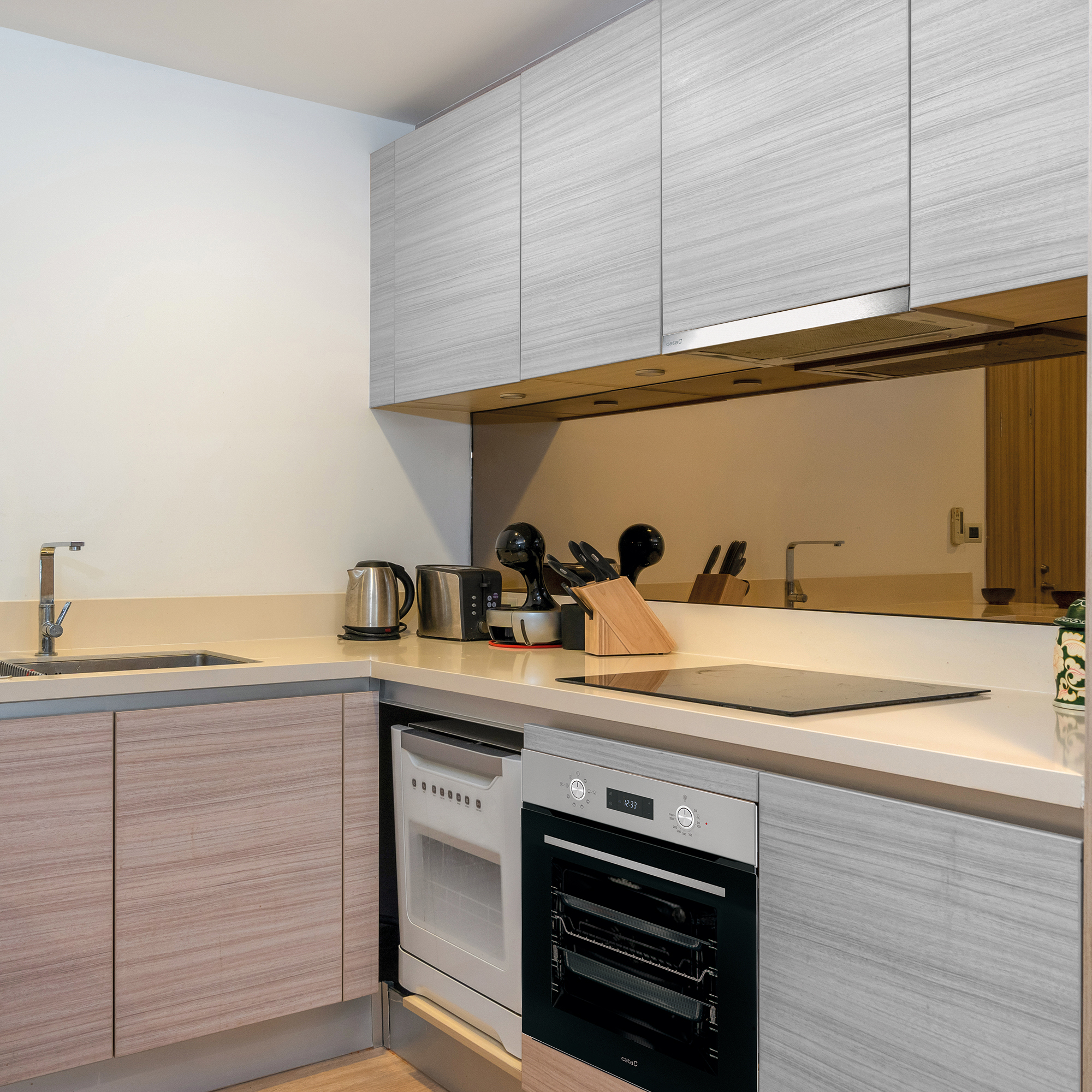 Cucina moderna con mobili in legno, lavello in acciaio inox ed elettrodomestici ad incasso.