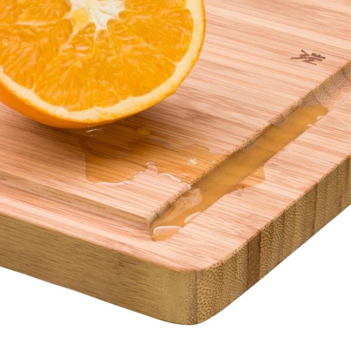Ein Holzschneidebrett mit einer halb geschnittenen Orange und Saft.