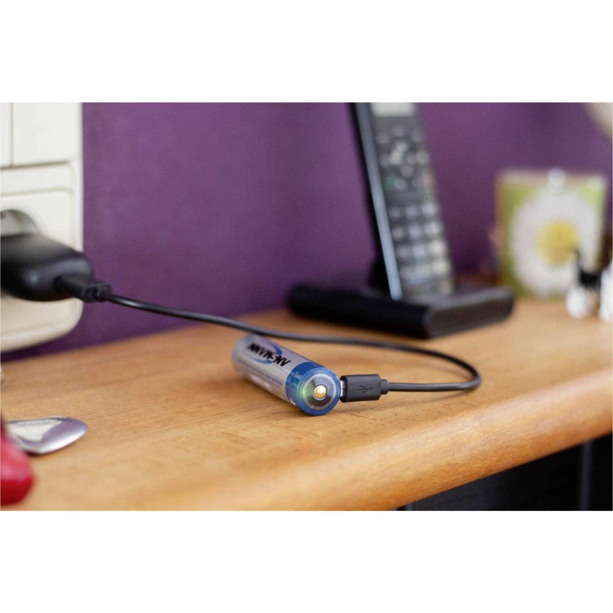 Een blauwgepunte AA-batterij die via een USB-kabel oplaadt naast een stopcontact en een telefoon.