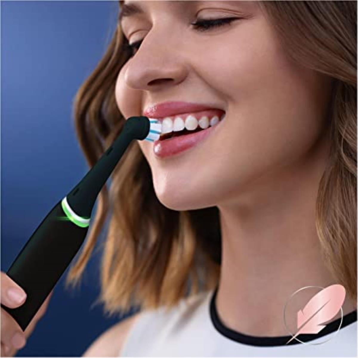 Kobieta myjąca zęby szczoteczką elektryczną.