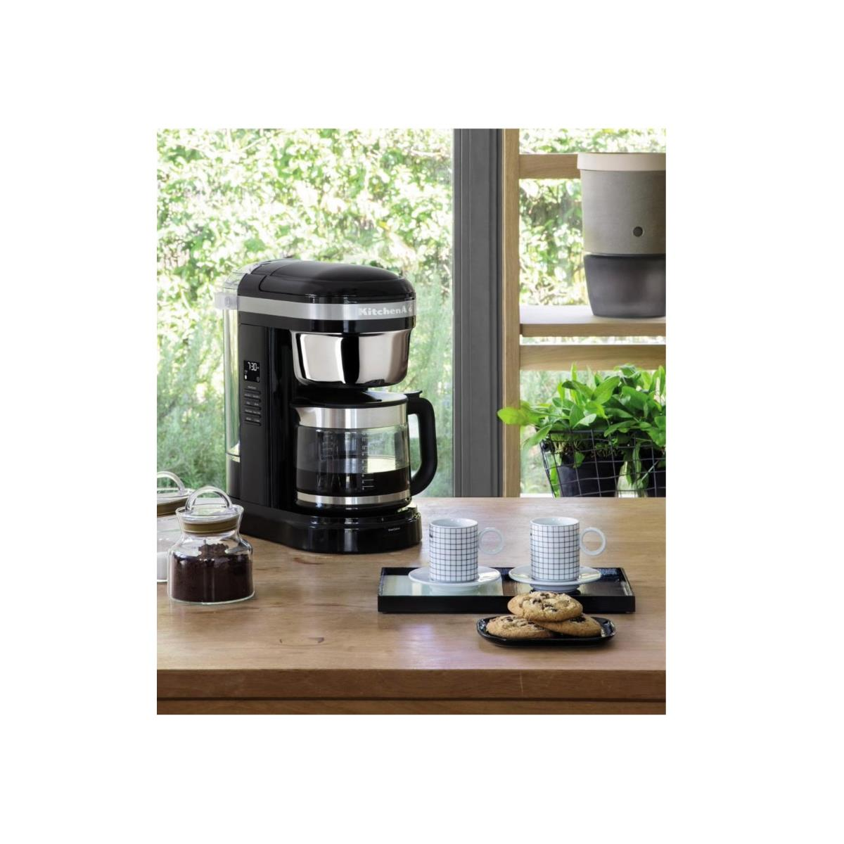 Czarny ekspres do kawy KitchenAid ze szklaną karafką, na drewnianym stole.