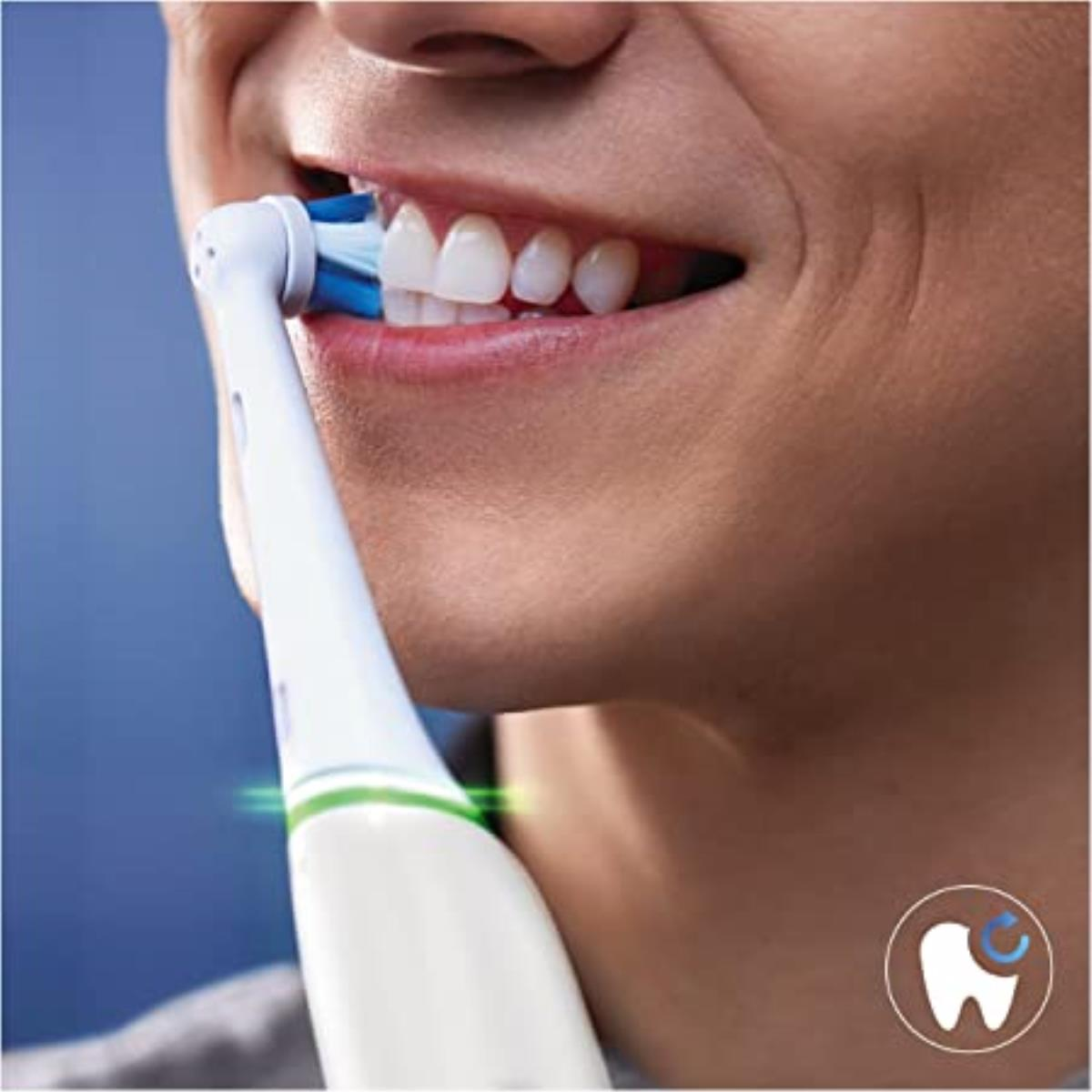 Una persona cepillándose los dientes con un cepillo eléctrico, primer plano de la boca.