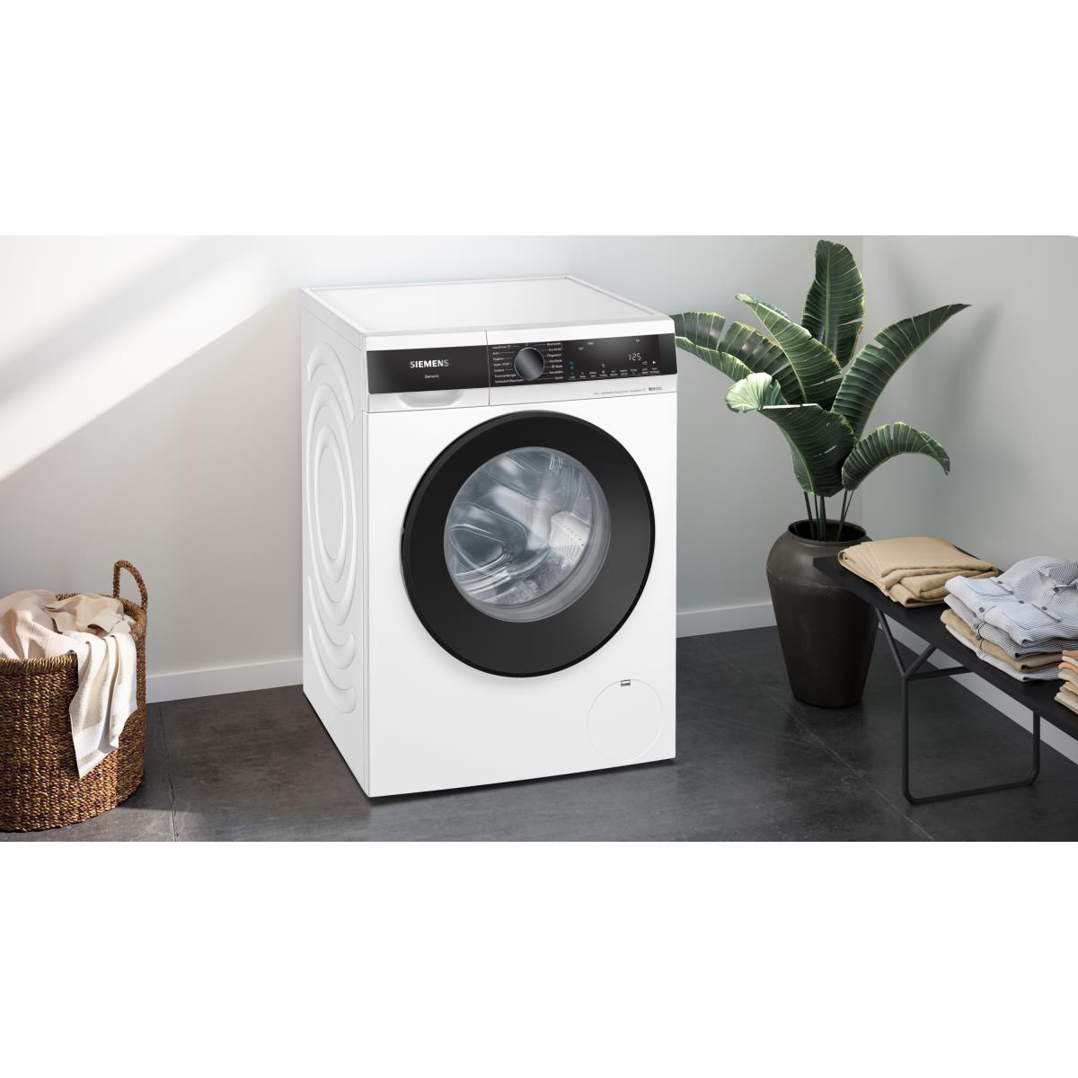 Eine weiße Siemens Waschmaschine mit schwarzer Tür und Korb. Eine Zimmerpflanze und Handtücher sind in der Nähe.