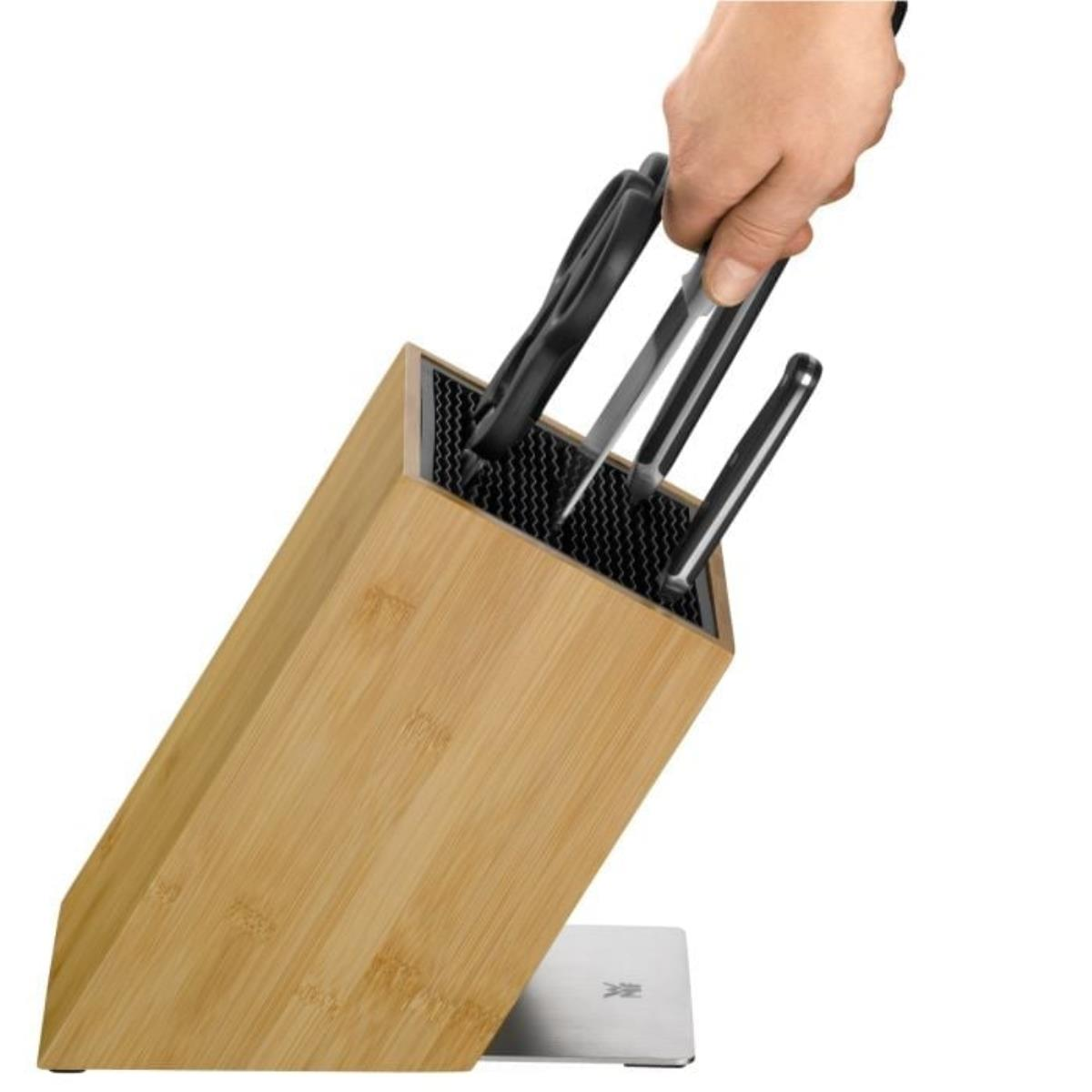 Eine Hand, die ein Messer aus einem Holz-Messerblock nimmt, hält den Griff.