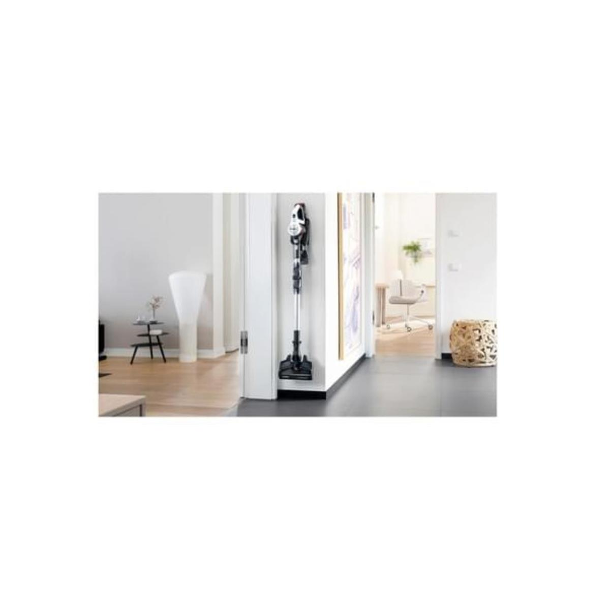 Bezprzewodowy odkurzacz oparty o ścianę, widoczny w przejściu. Ustawienie to nowoczesne mieszkanie.