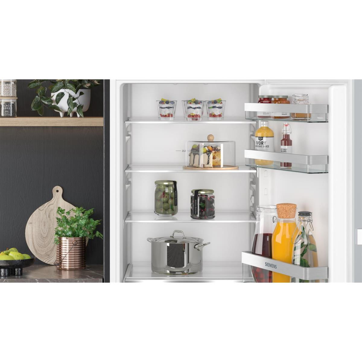 Refrigerator interior with various items: jars, desserts, and food in glass containers. White background.