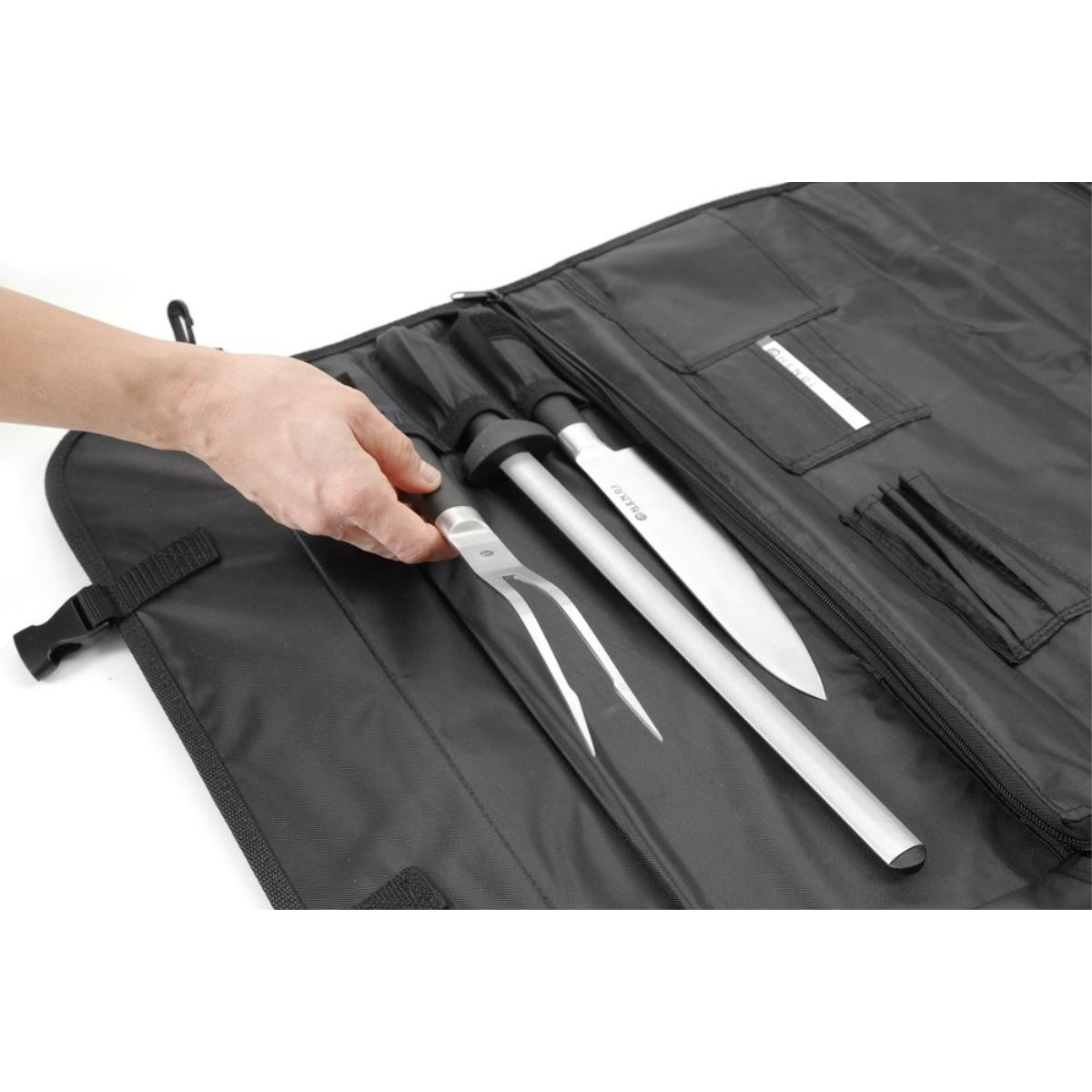Eine Hand, die in eine schwarze Messertasche greift, die Messer und einen Wetzstahl enthält.