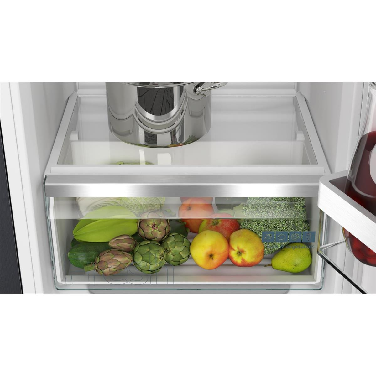 In een koellades: groenten, fruit en een pot. Achtergrond is het interieur van de koelkast.