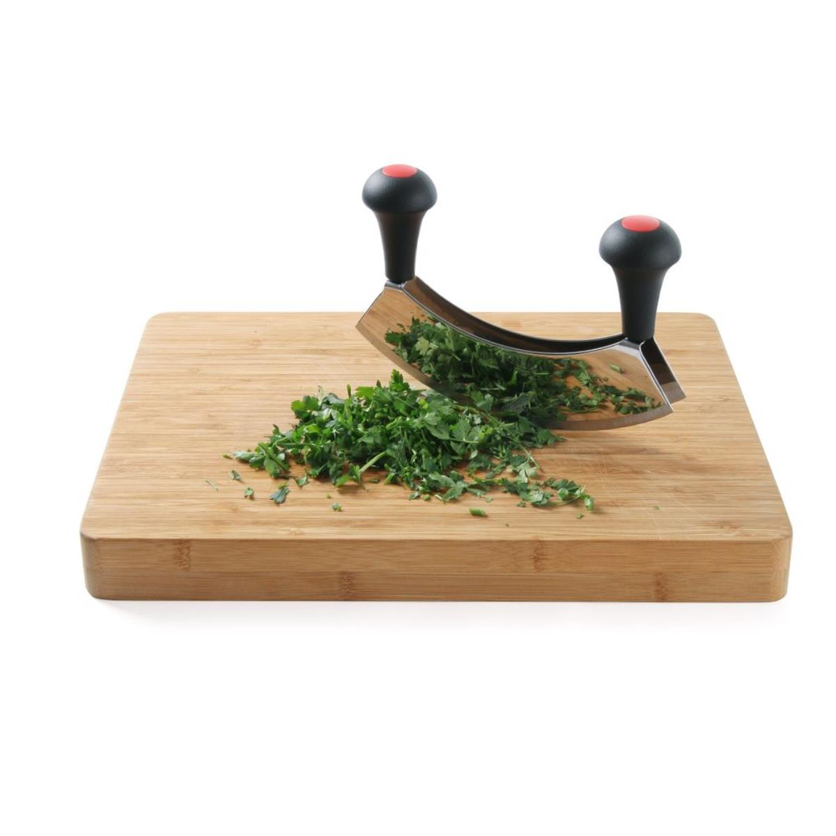 Ein Kräutermesser auf einem Holzschneidebrett mit gehackten Kräutern.