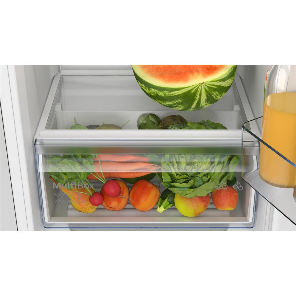 Kühlschrank mit einer Schublade voller Obst und Gemüse. Oben liegt eine Wassermelone.