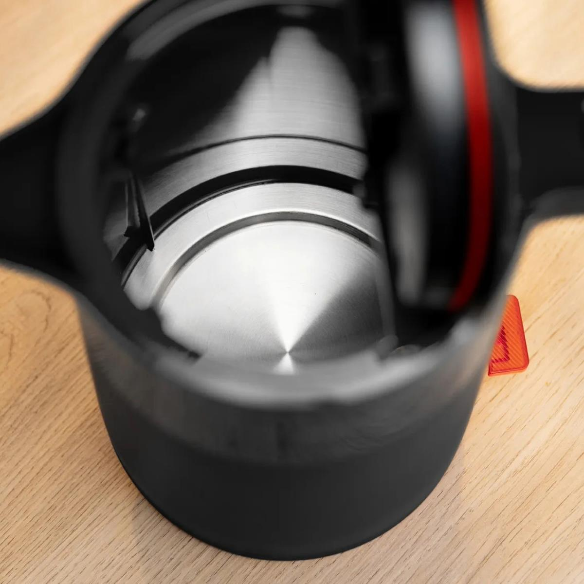 Widok od wewnątrz czajnika elektrycznego, wnętrze ze stali nierdzewnej, na drewnianym stole.