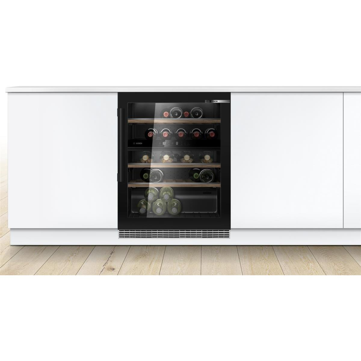 Una vinoteca empotrada con botellas de vino en su interior, contra un mueble blanco.