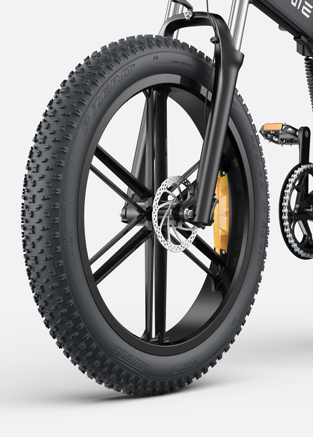 Primer plano de una rueda de bicicleta eléctrica negra con un neumático grueso. Detalle de freno naranja visible.