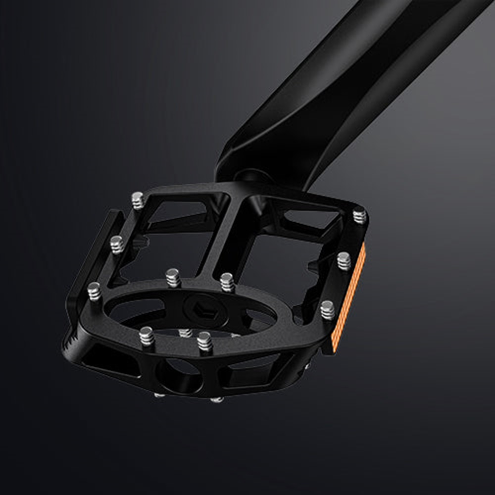 Pedal de bicicleta negro con un reflector de seguridad y fondo negro.