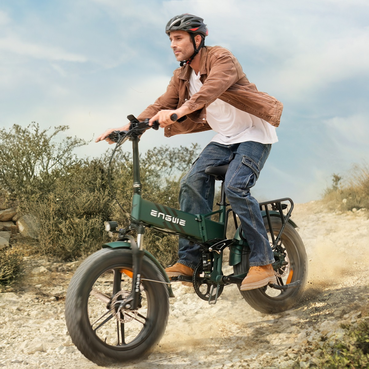 Un hombre monta en una bicicleta eléctrica verde en un camino de tierra, usando un casco.