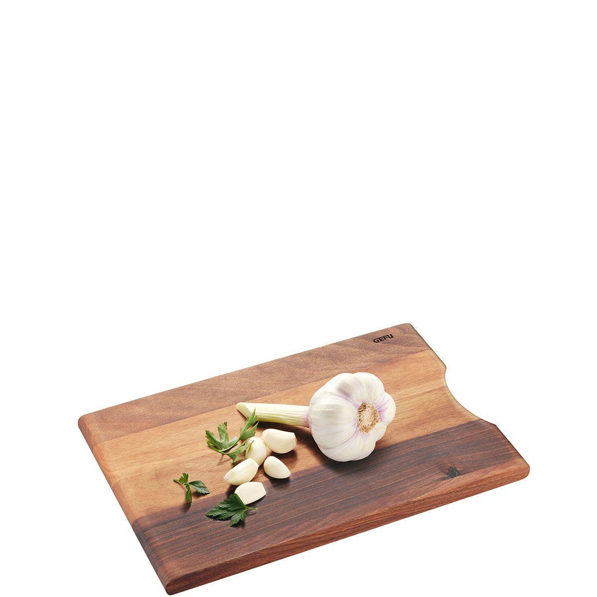 Holzschneidebrett mit Knoblauch, Petersilie und Knoblauchzehen auf weißem Hintergrund.