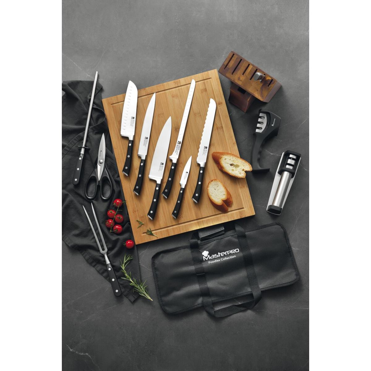 Una colección de cuchillos, tijeras y otras herramientas de cocina sobre una tabla de madera y una superficie oscura.