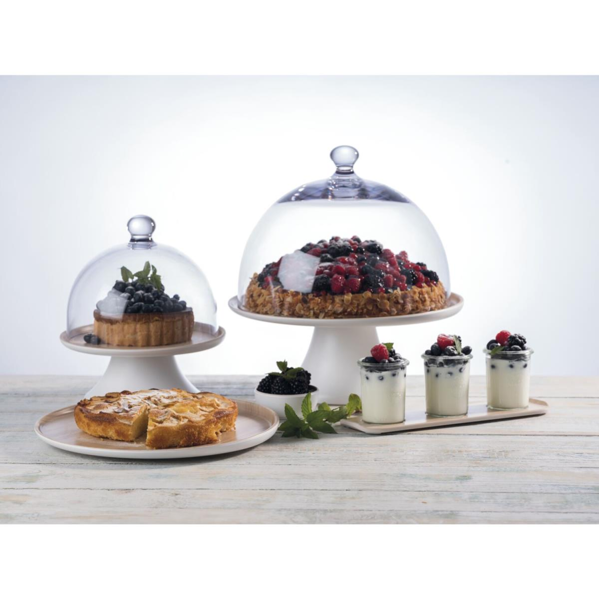 Desserts auf einem Holztisch: Kuchen, Torten und Parfaits unter Glasglocken.