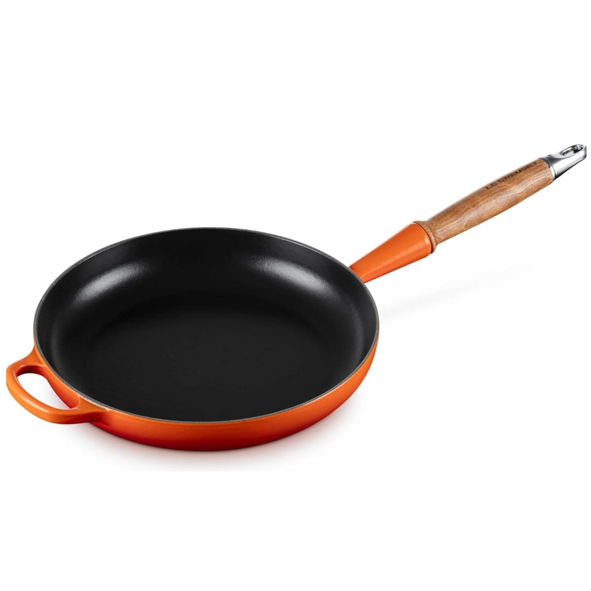 Eine orangefarbene Le Creuset Bratpfanne mit schwarzer Innenseite, Holzgriff und silbernem Griffansatz.