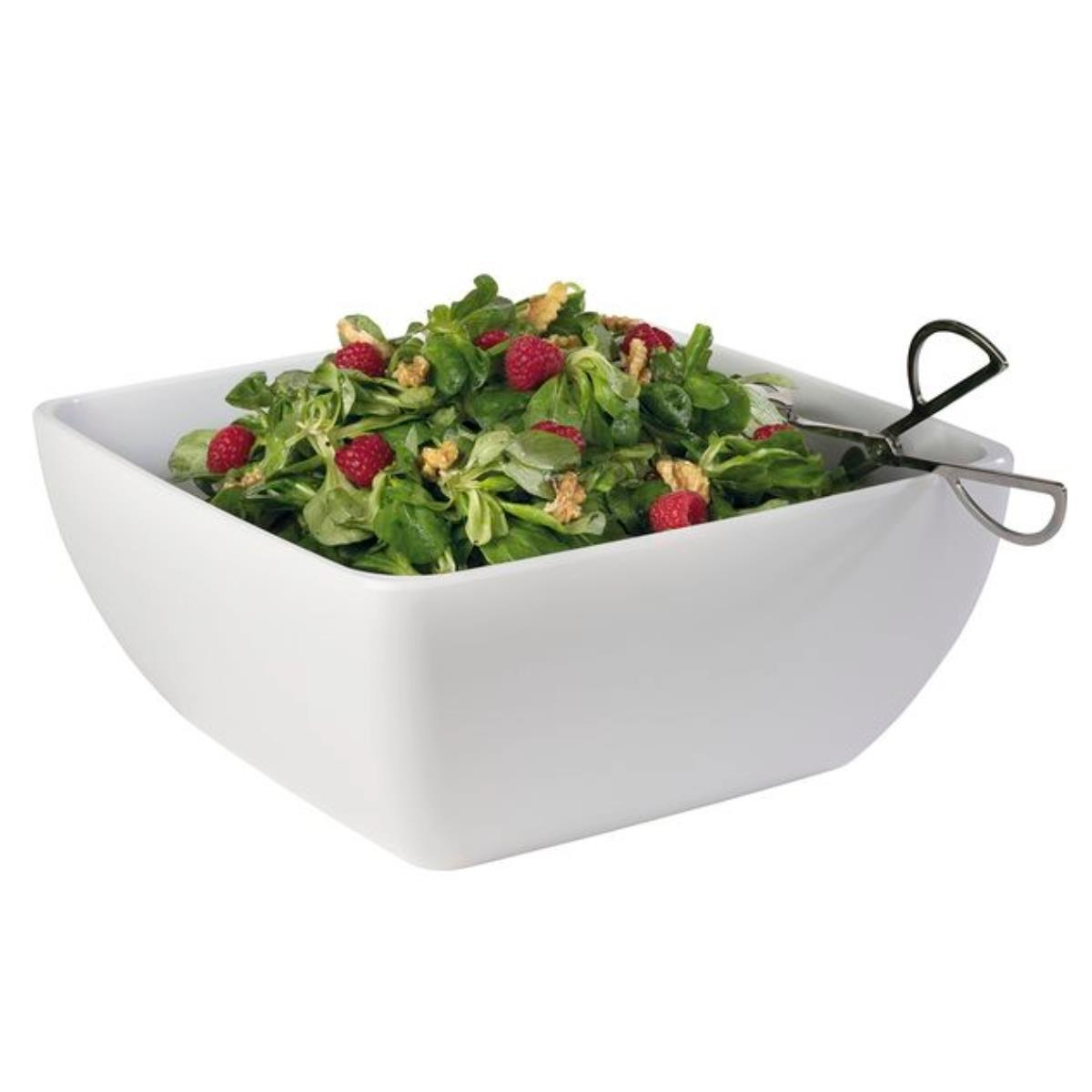 Eine weiße quadratische Schüssel gefüllt mit Salat, roten Beeren und Zangen.