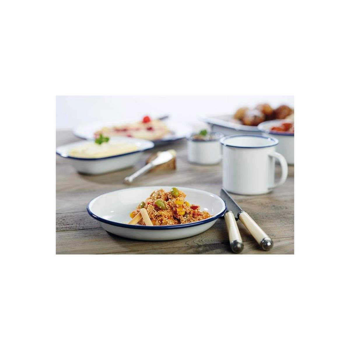 Ein Teller mit Essen, Besteck und eine Tasse auf einem Holztisch, andere Gerichte im Hintergrund.