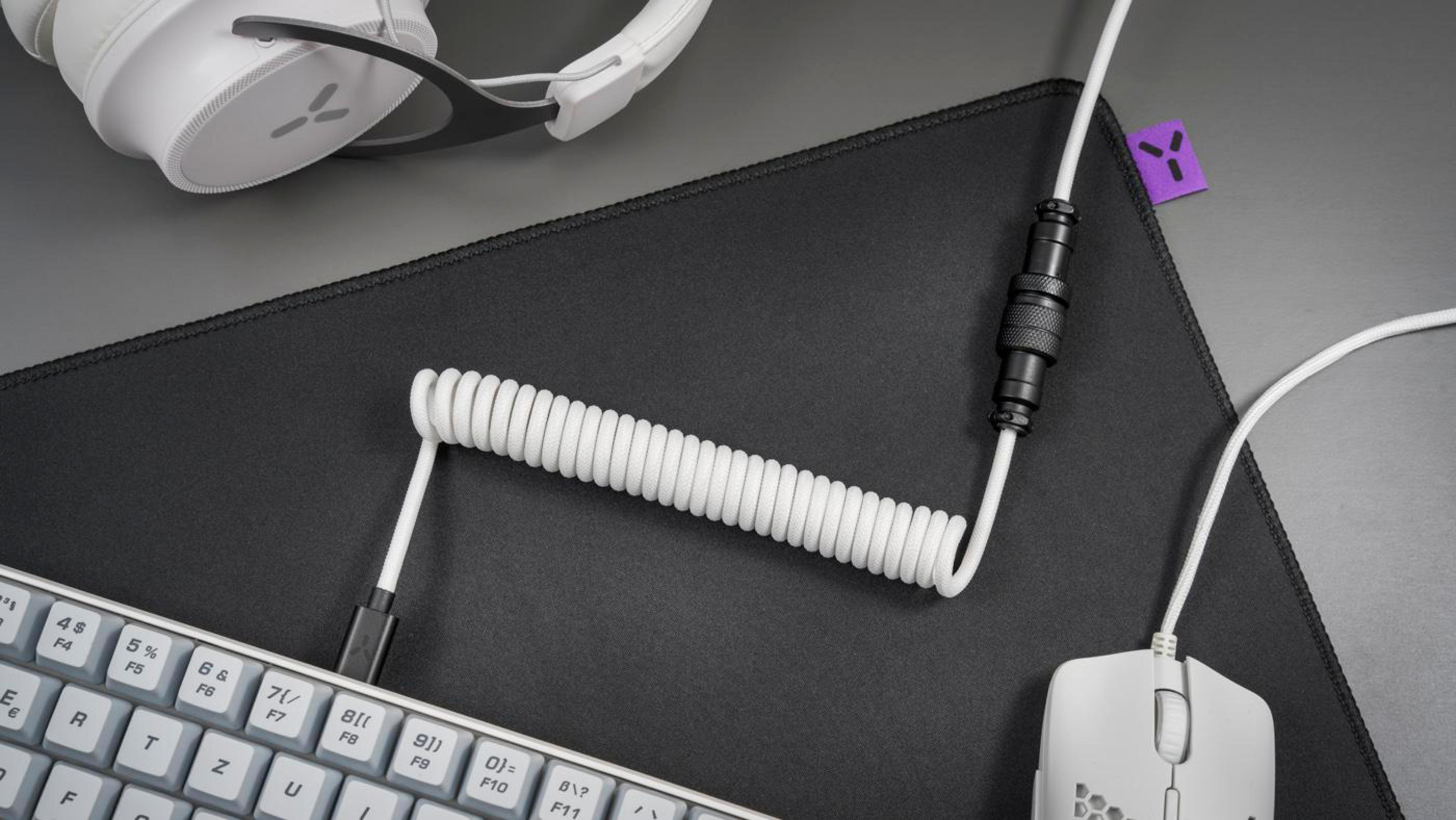 Weißes Spiralkabel, das mit Tastatur, Maus und Headset verbunden ist.