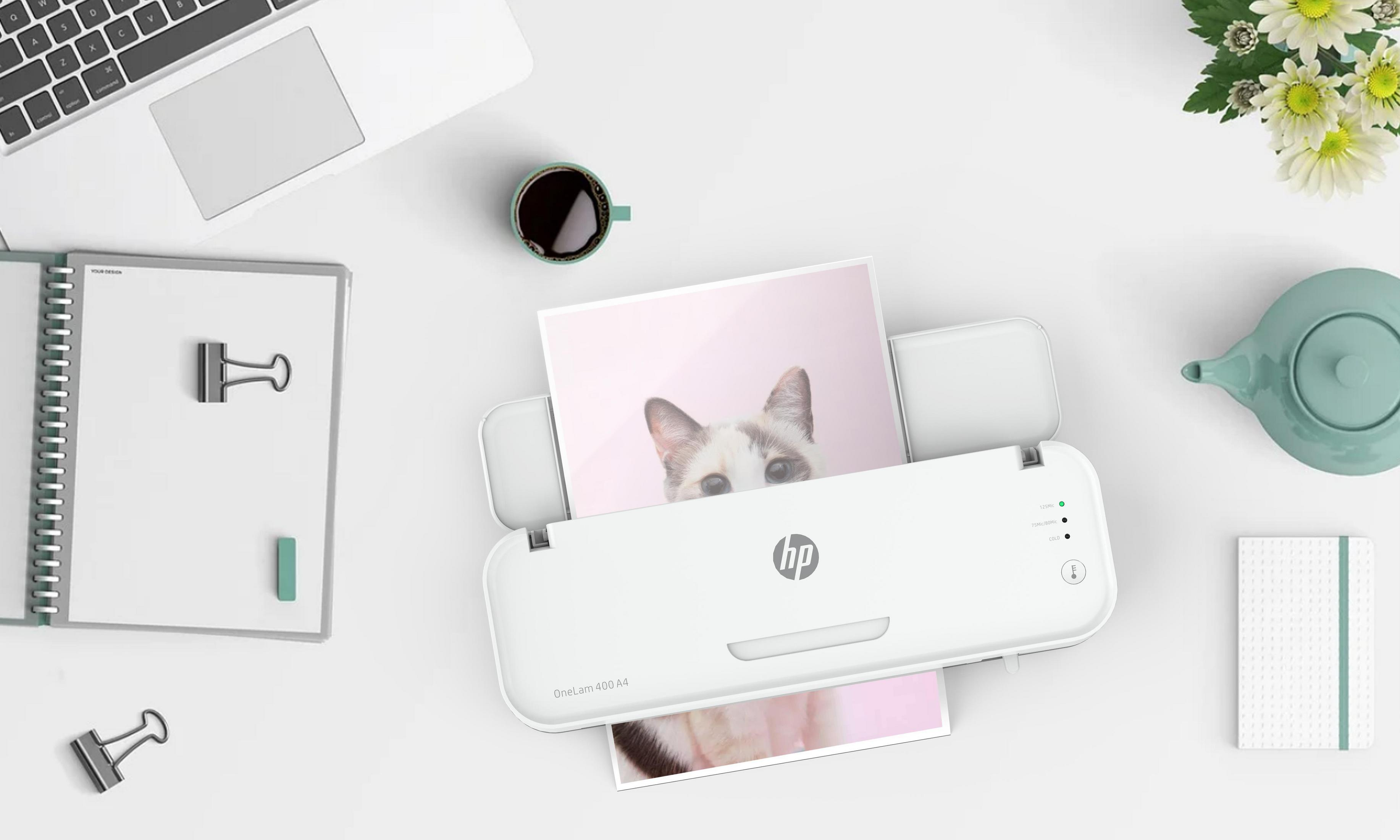 Biała drukarka drukująca zdjęcia na białym biurku. Widoczne inne przedmioty.