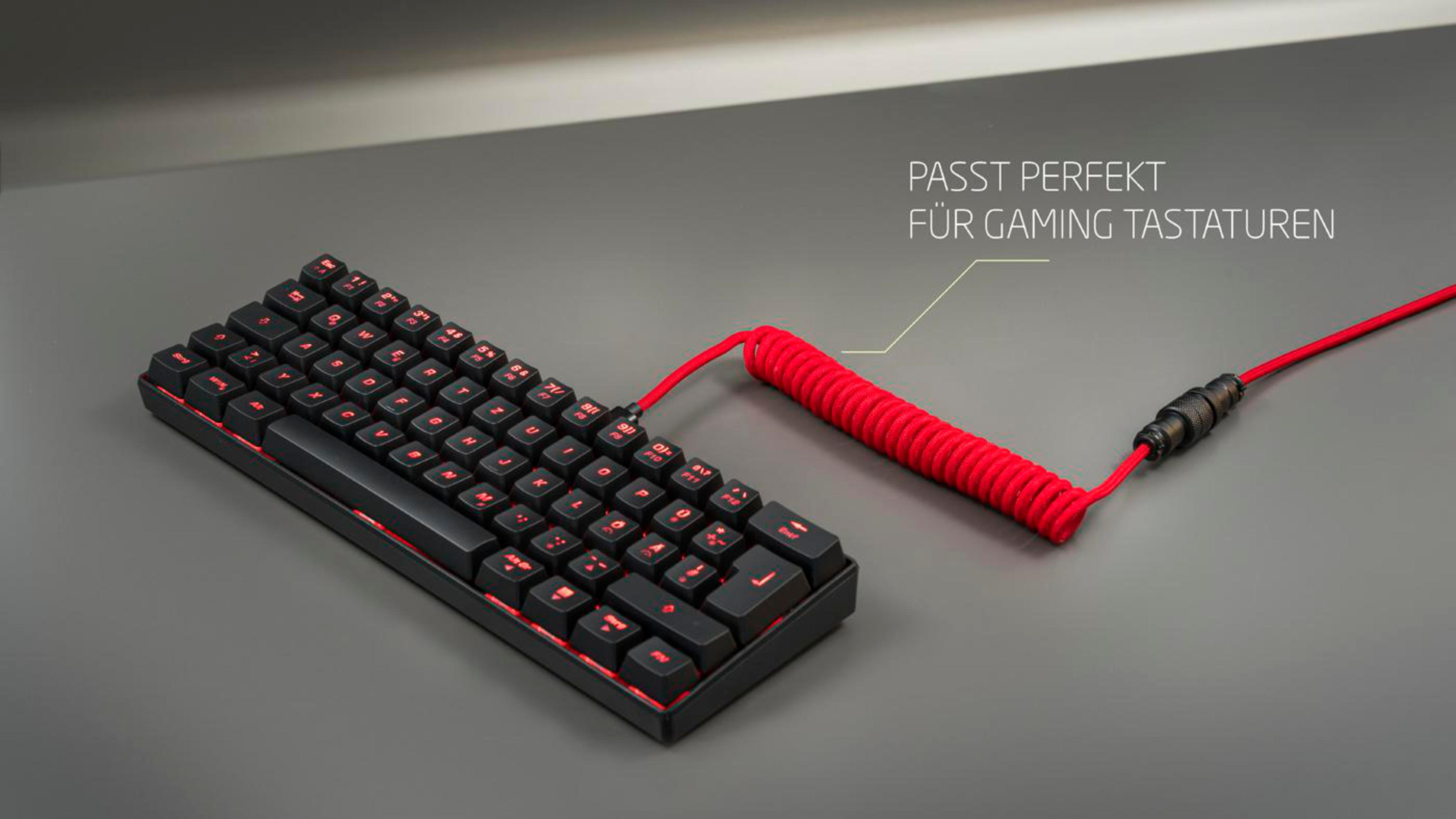 Schwarze Gaming-Tastatur mit roten Lichtern und einem gewendelten roten Kabel auf grauer Oberfläche.