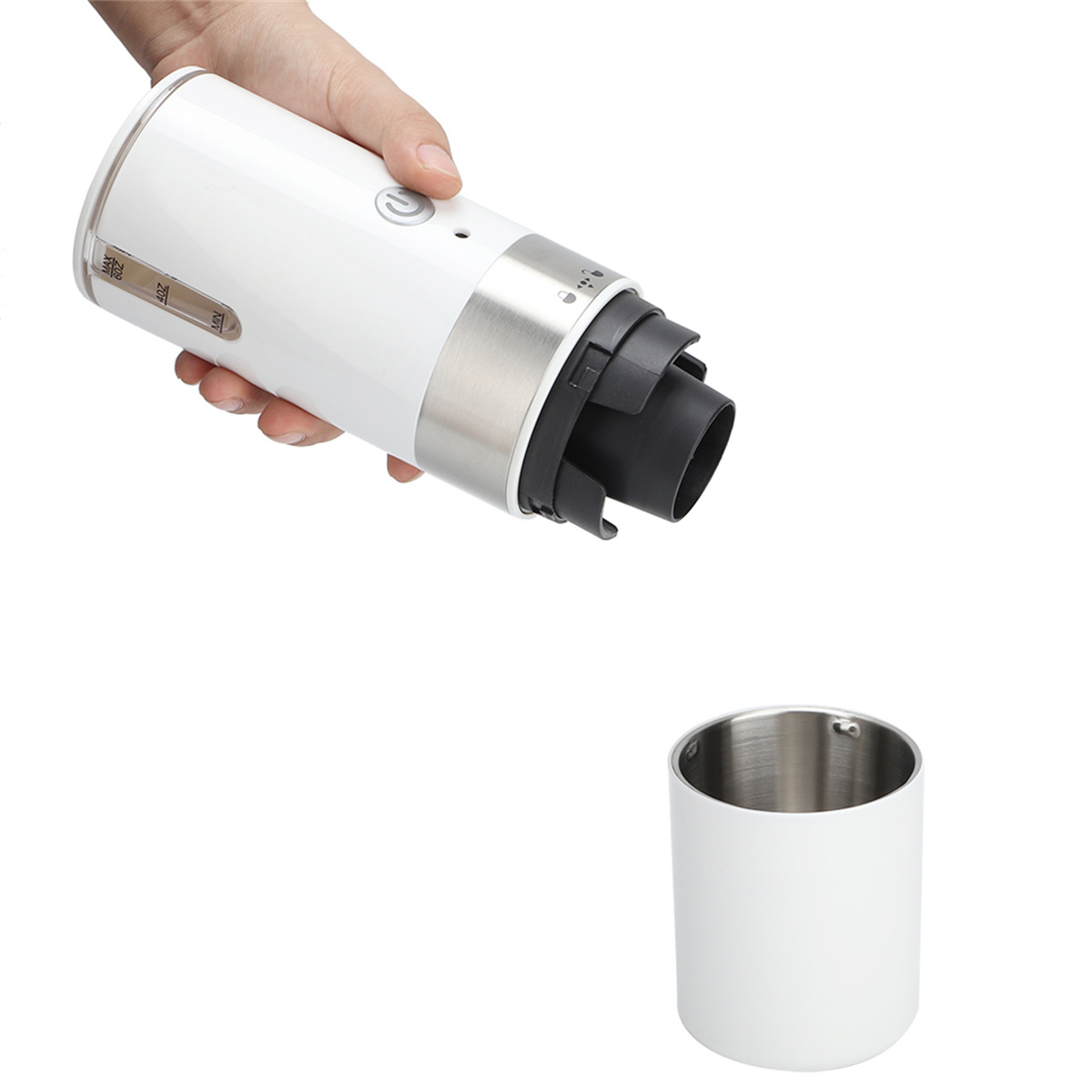 Eine Hand, die ein weißes, zylindrisches Objekt mit einem silbernen Band hält. Darunter ein weißer Becher.