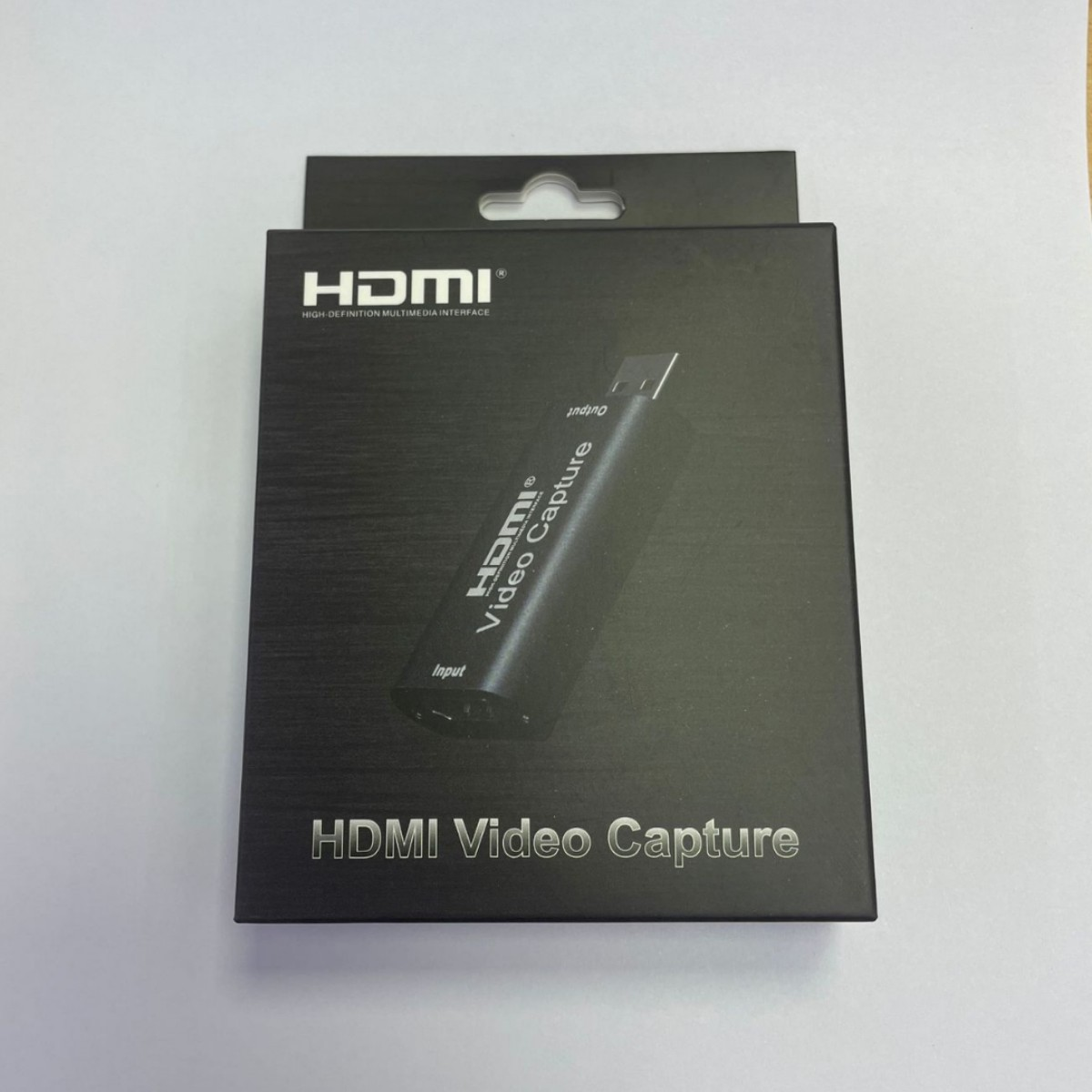 Ein schwarzes HDMI-Videoaufnahmegerät in einer schwarzen Box, mit HDMI- und USB-Anschlüssen.