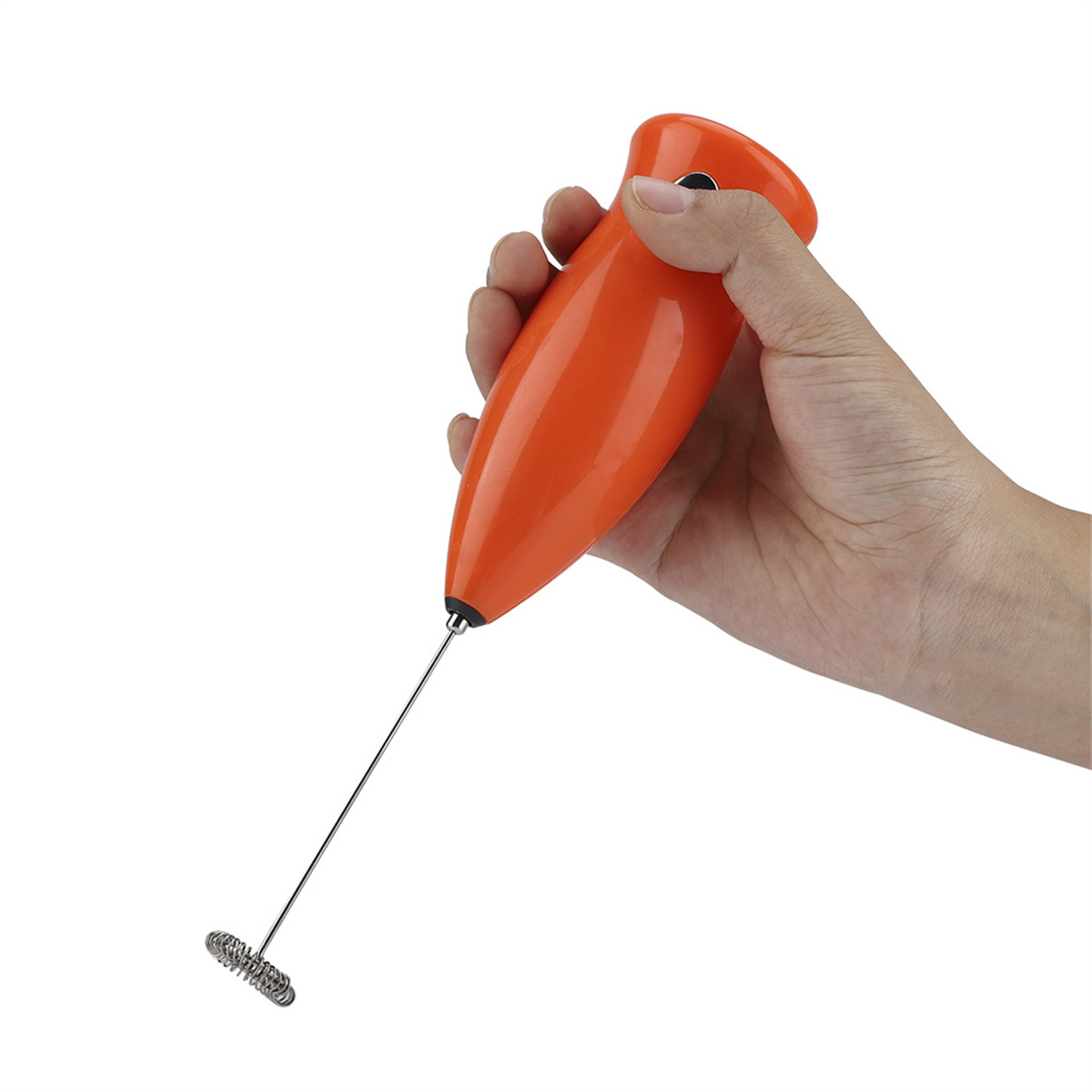 Hand, die einen orangenen elektrischen Milchaufschäumer mit einem silbernen Schneebesen hält.