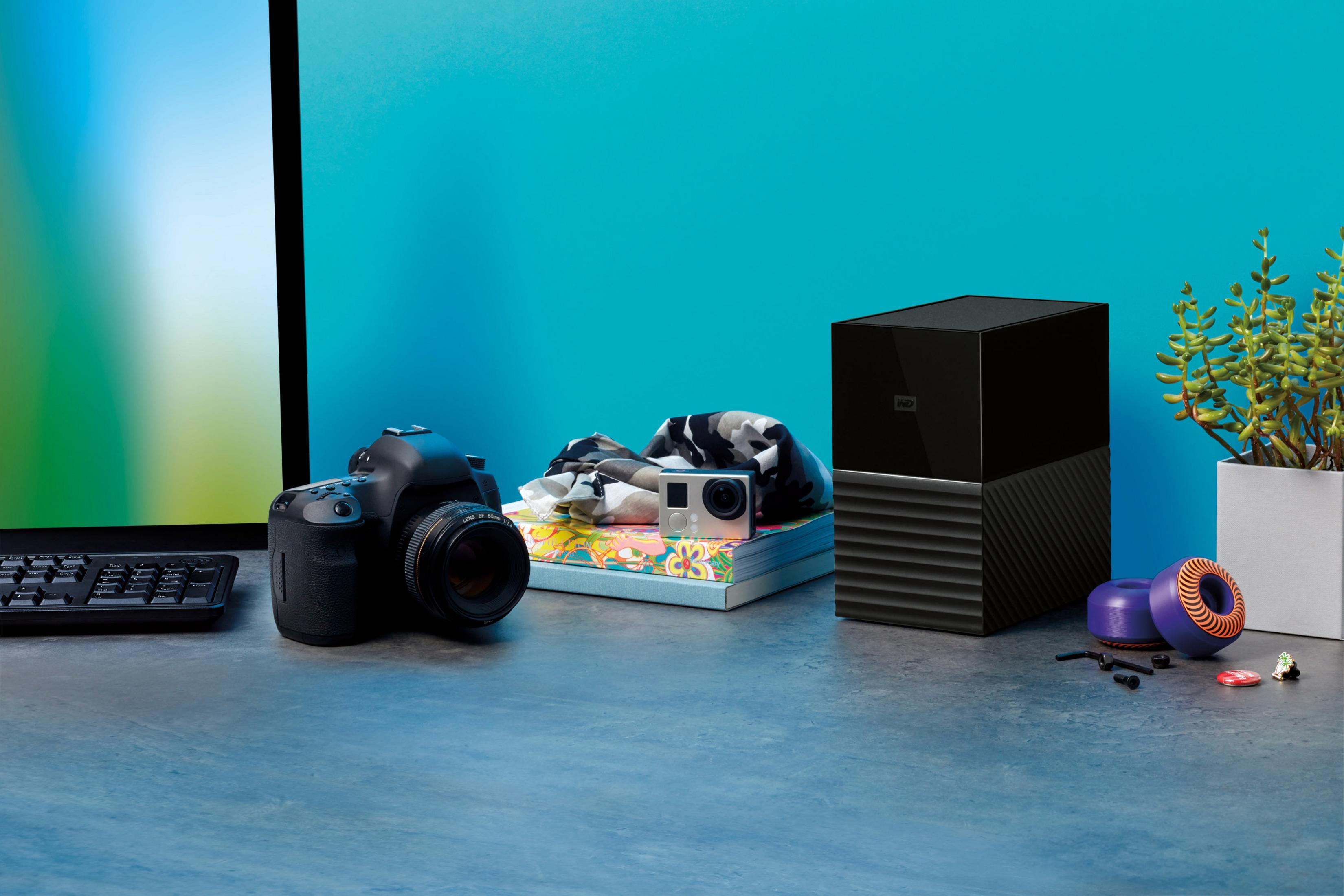 Scena na biurku z aparatem, monitorem, dyskiem twardym i innymi przedmiotami.