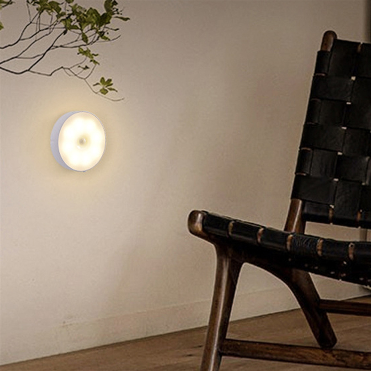 Eine weiße Wand mit einer kreisförmigen, beleuchteten Wandlampe und einem Holzstuhl.