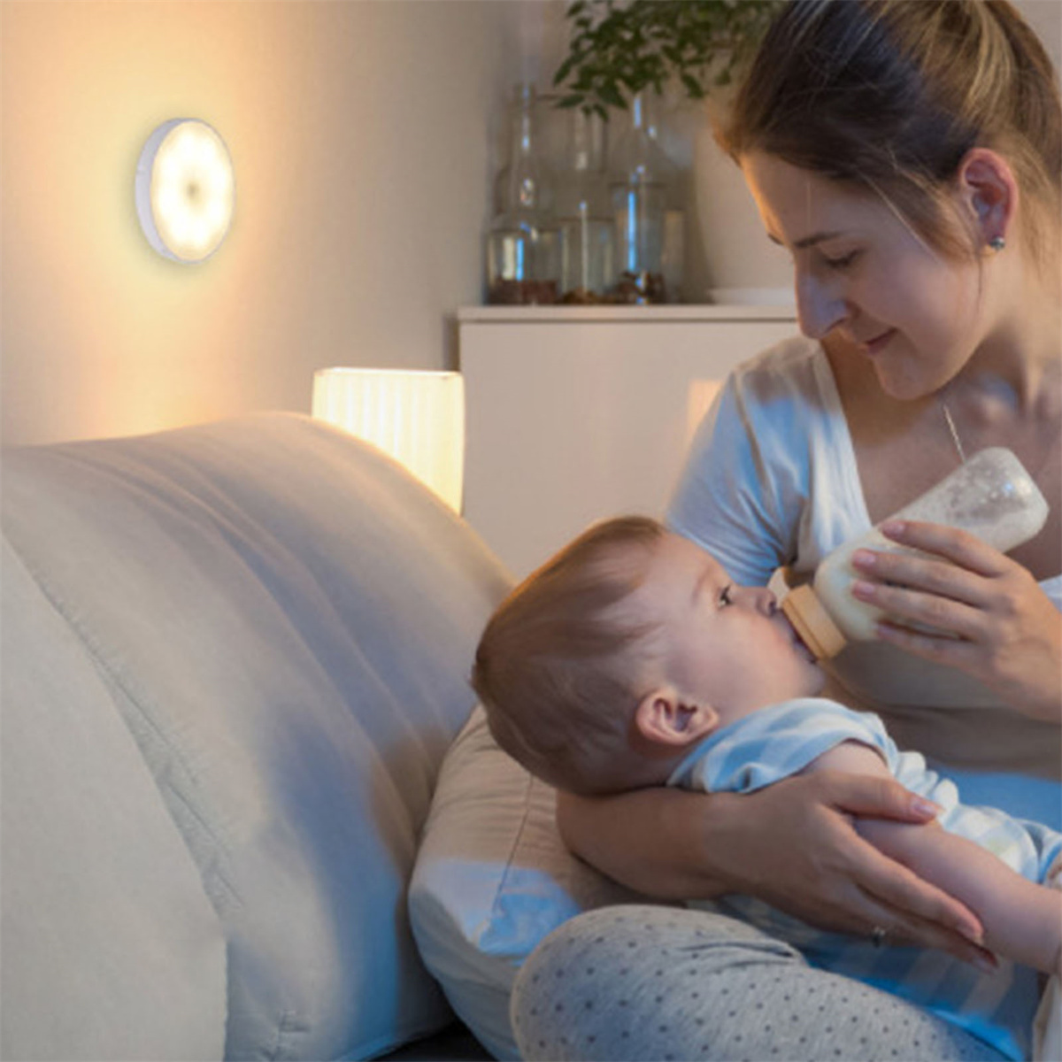 Eine Mutter füttert ein Baby mit einer Flasche unter sanftem Licht.