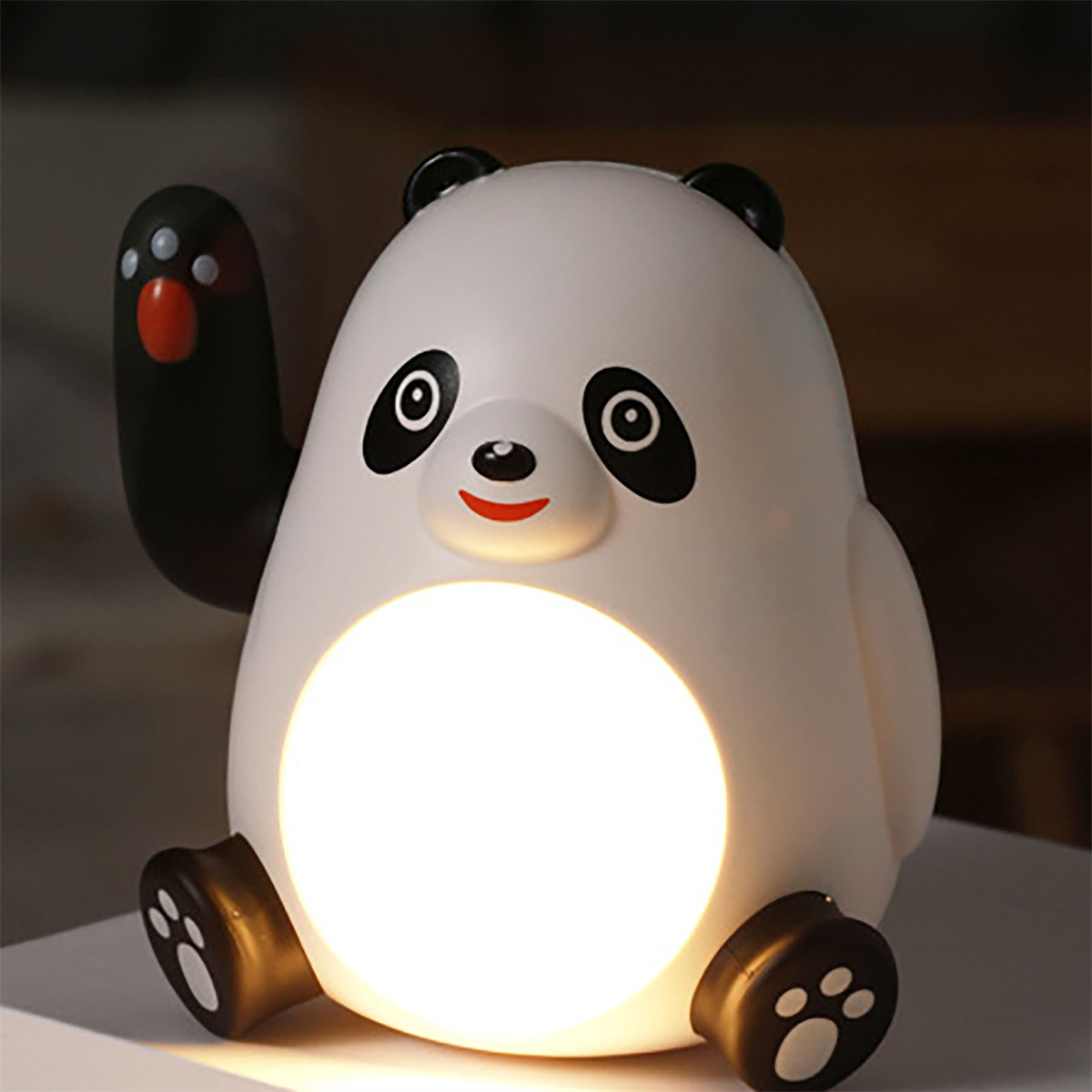 Eine weiße Panda-Lampe mit winkendem Arm. Die Lampe steht auf einer Oberfläche.