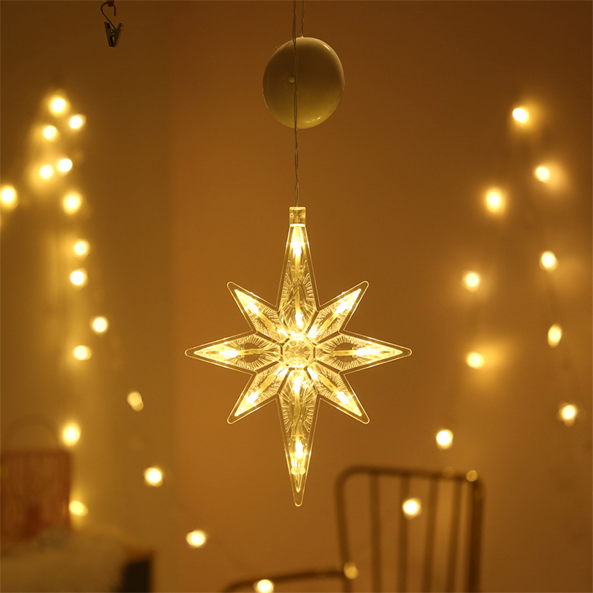Ein sternförmiges dekoratives Licht, das von einer Decke hängt, mit Lichterketten im Hintergrund.