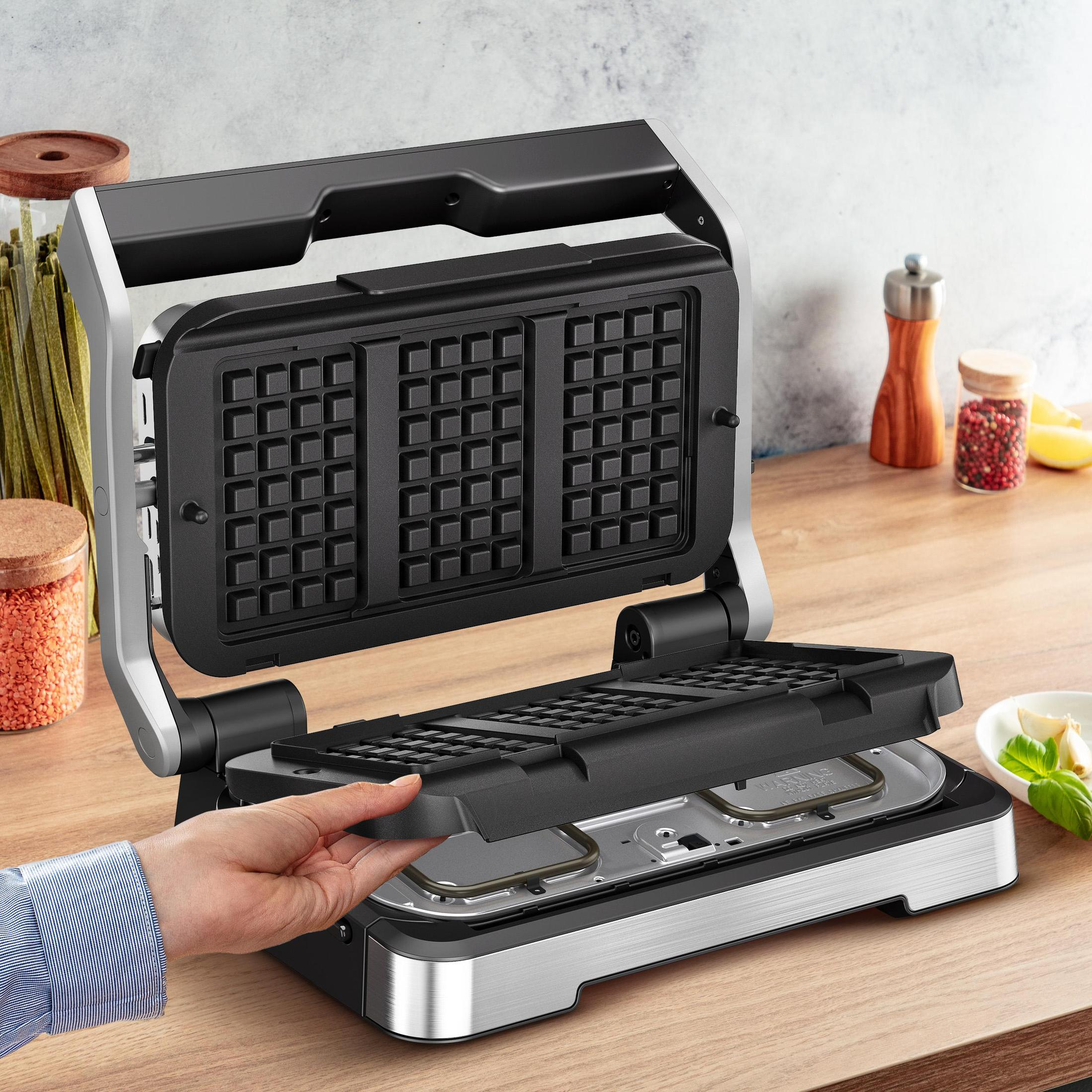 Waffeleisen geöffnet, mit herausnehmbaren Platten, auf Holzoberfläche.