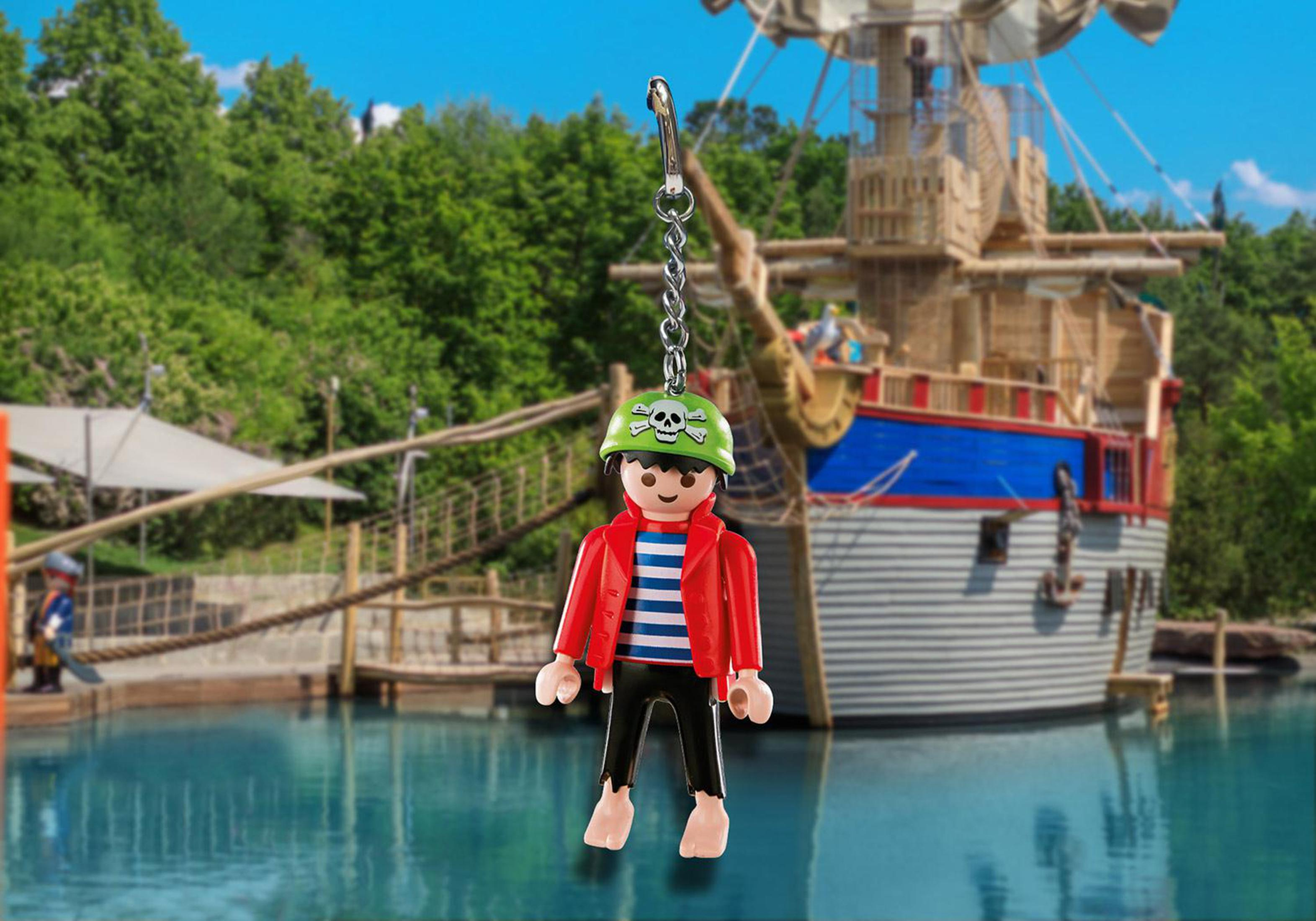 Ein Spielzeugpirat hängt vor einem Piratenschiff. Grüne Bäume und blaues Wasser bilden den Hintergrund.
