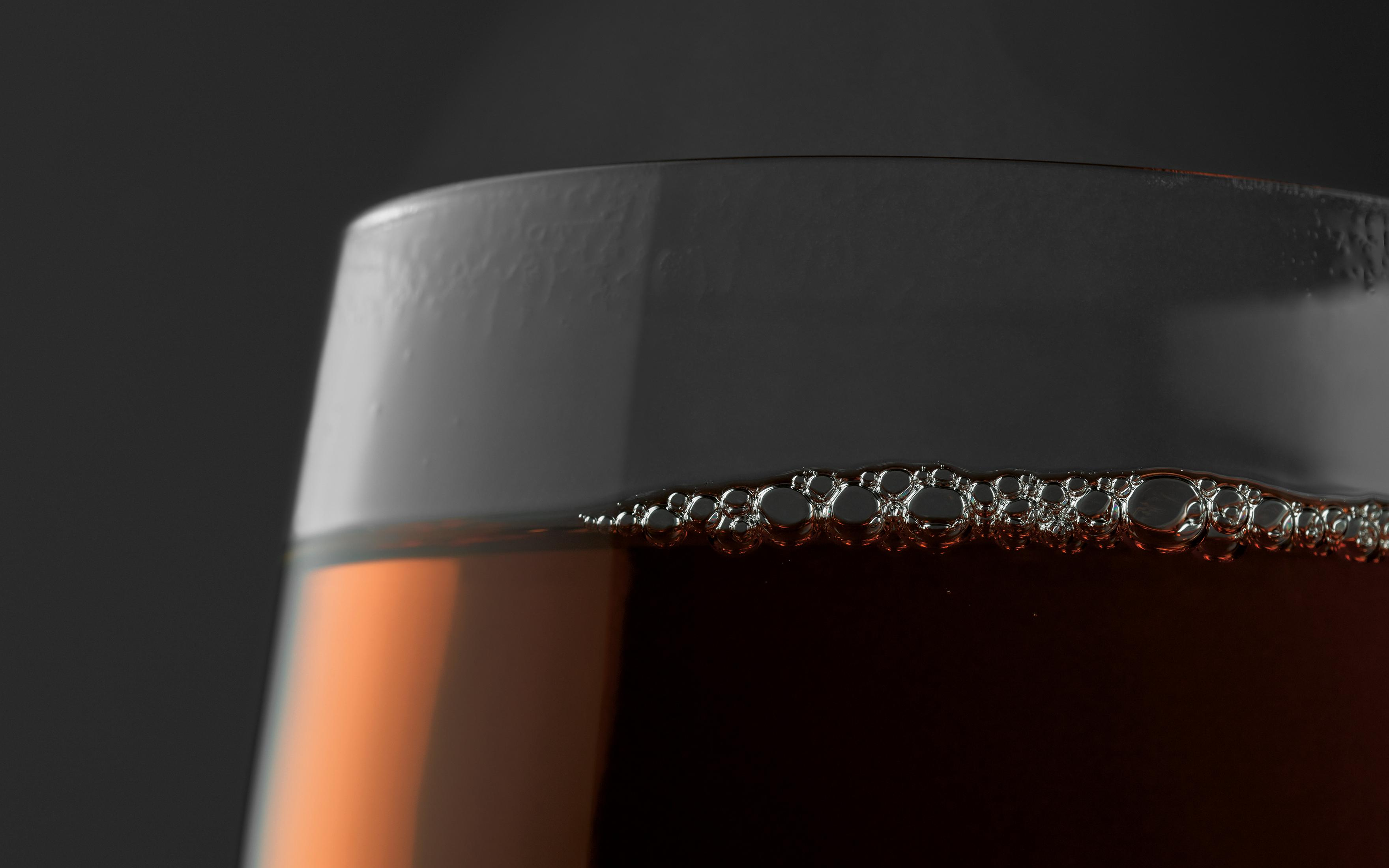 Nahaufnahme eines Bierglases mit sichtbaren Blasen auf der Oberfläche.