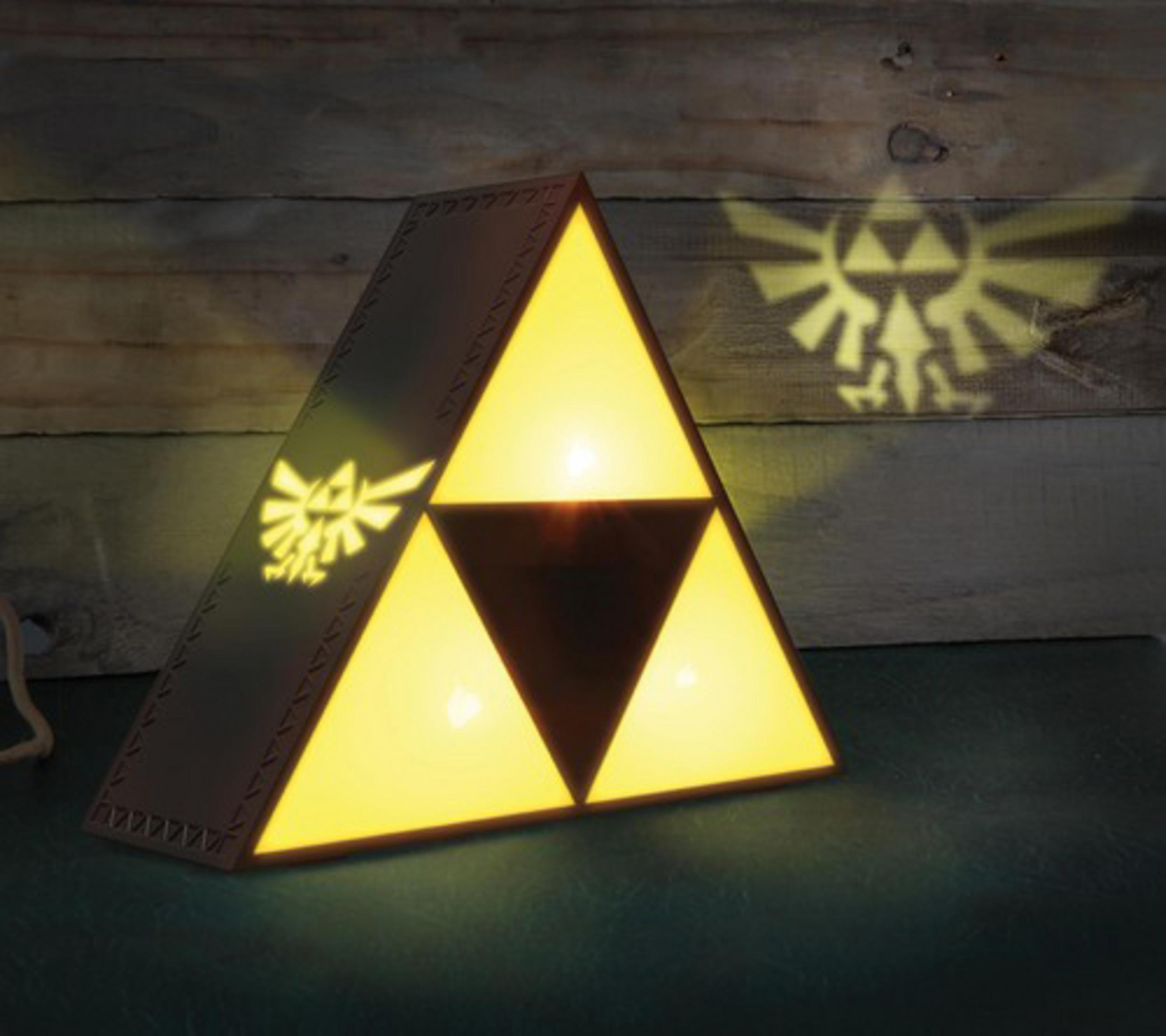 Eine dreieckige Lampe mit dem Zelda-Logo. Es projiziert das Logo auf den Hintergrund.