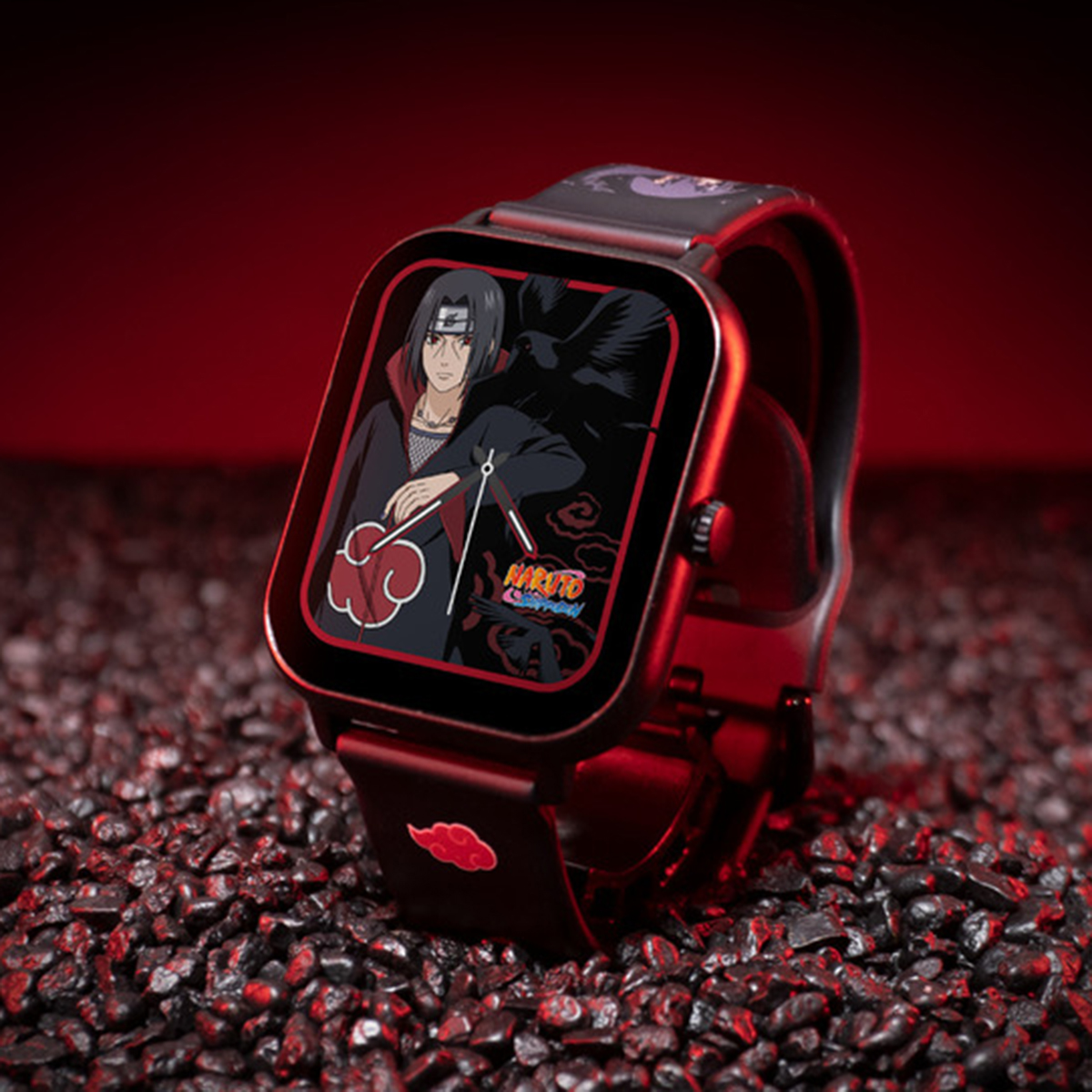 Uno smartwatch con un design di personaggi di Naruto, su ciottoli scuri contro uno sfondo rosso.