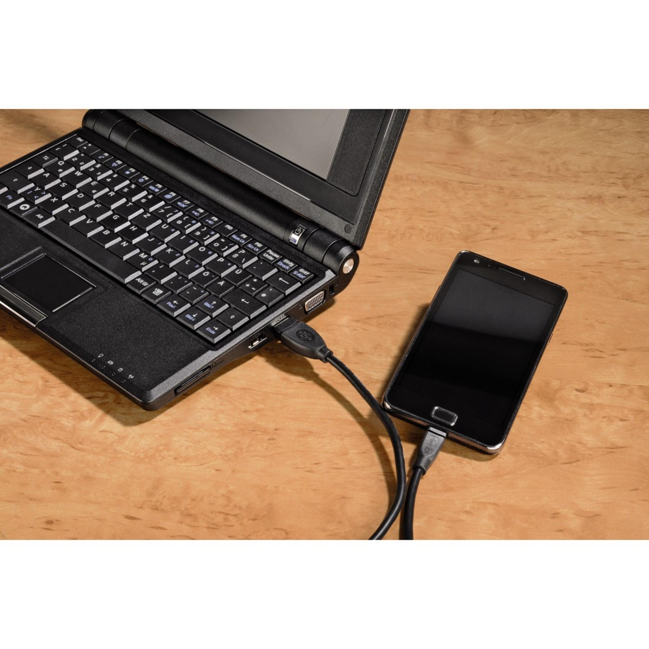 Laptop über USB-Kabel mit Smartphone auf Holzoberfläche verbunden.