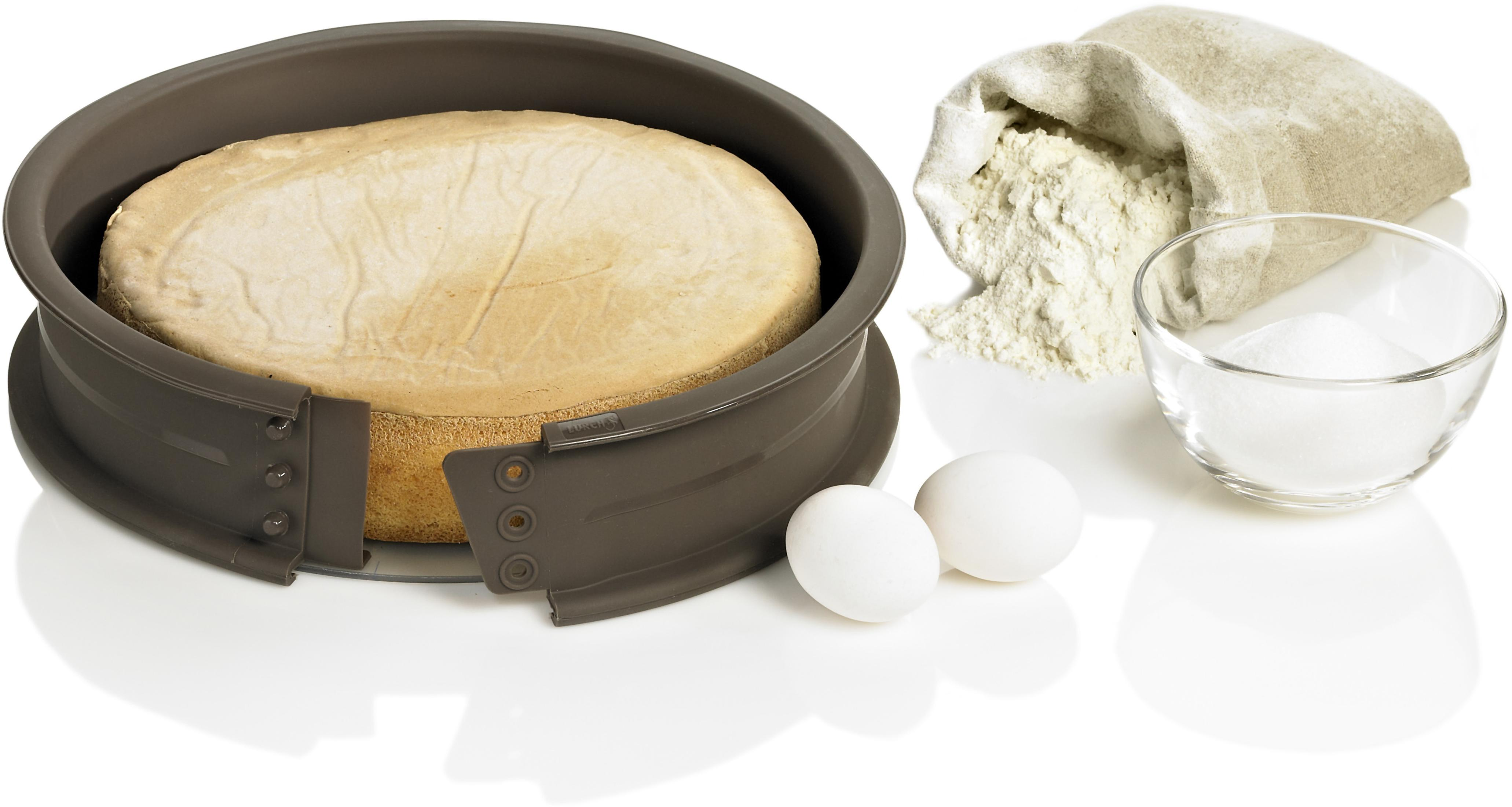 Ciasto w brązowej formie do pieczenia z mąką, cukrem i jajkami na białej powierzchni.