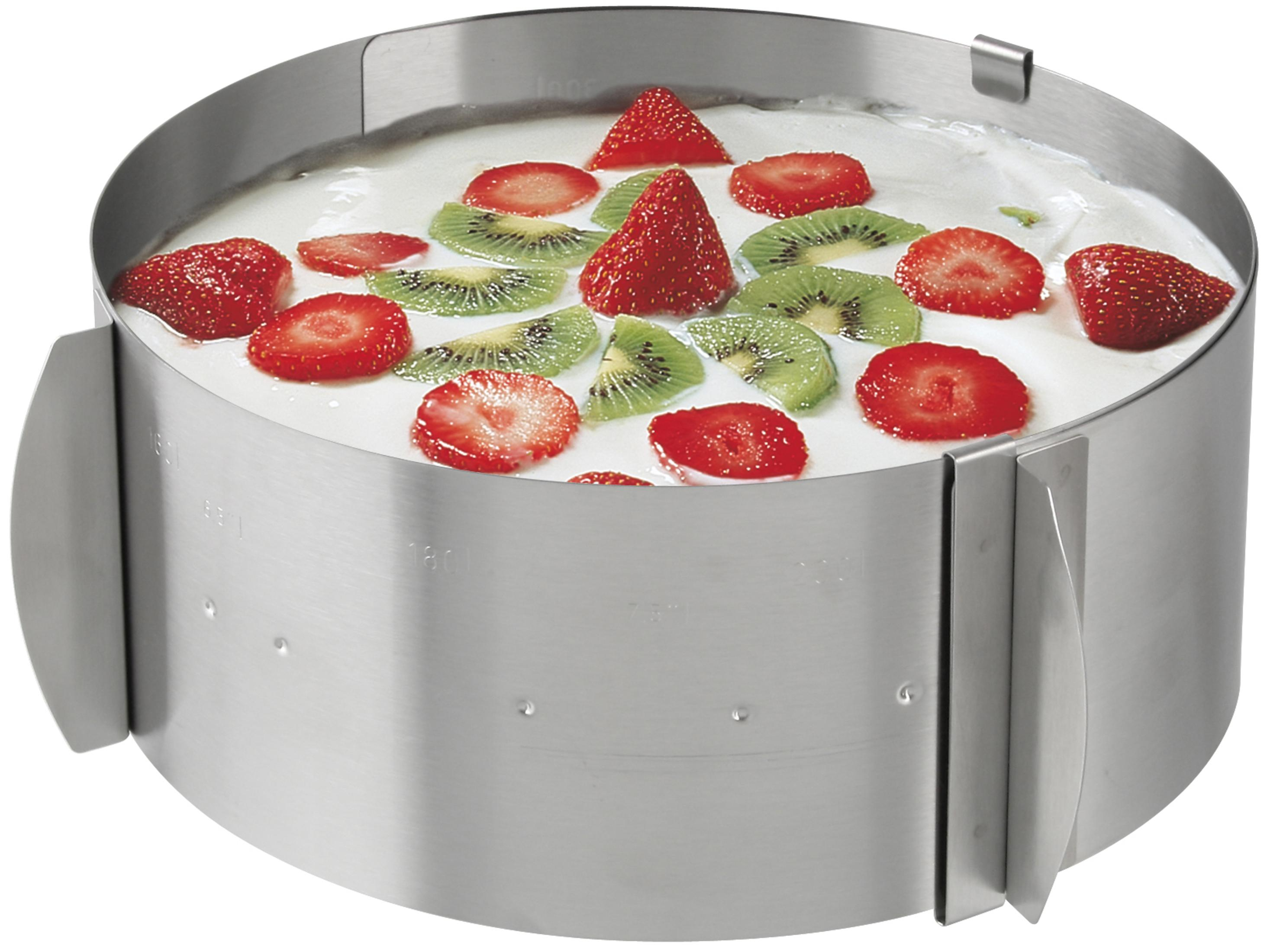 Kuchen in einem Metallring mit Schlagsahne, Erdbeeren und Kiwischeiben.