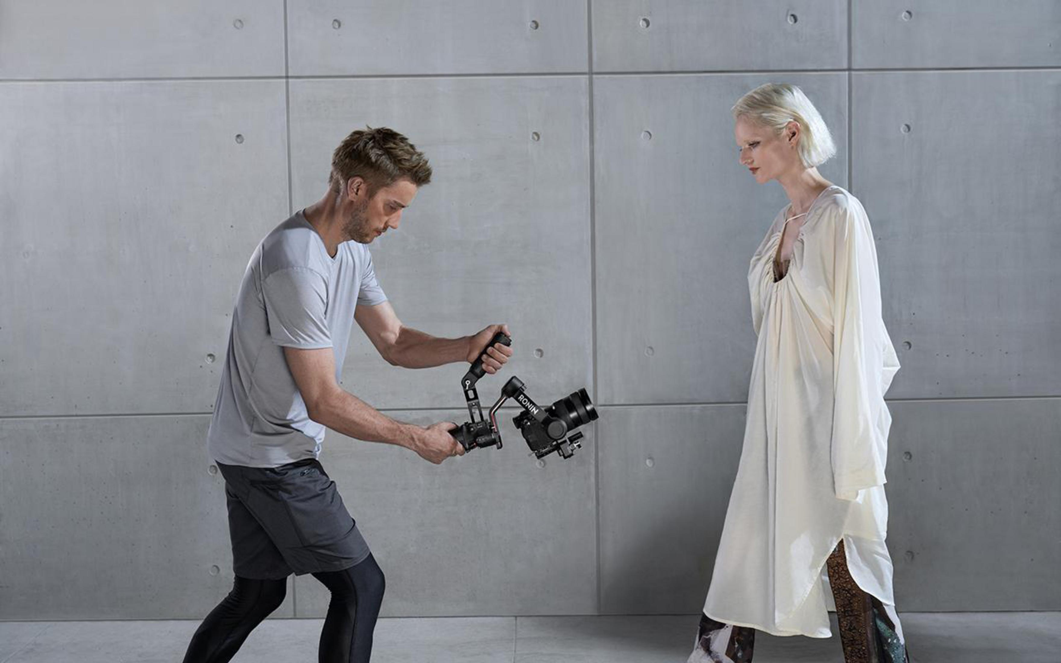 Un uomo filma una donna in abito bianco con una fotocamera su un gimbal.
