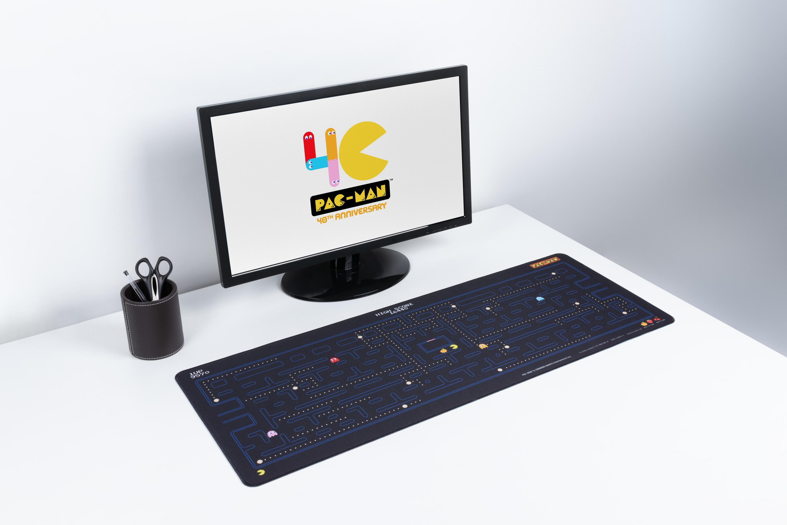Ein Schreibtisch mit einem Computermonitor, der ein Pac-Man-Logo zeigt. Eine Pac-Man-Spielmatte und ein Stifthalter sind sichtbar.