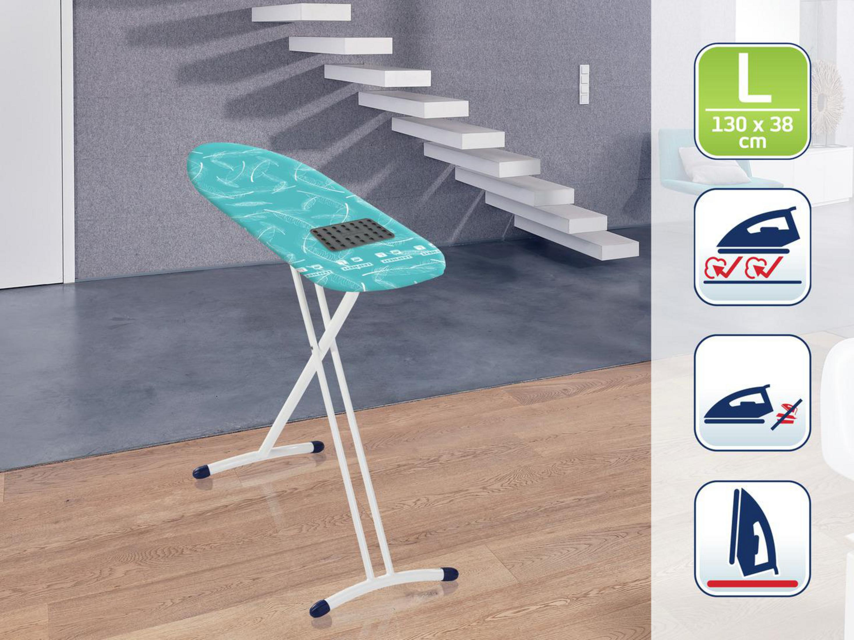 Deska do prasowania, turkusowa osłona z białym wzorem piór. W pokoju ze schodami i szarą ścianą.